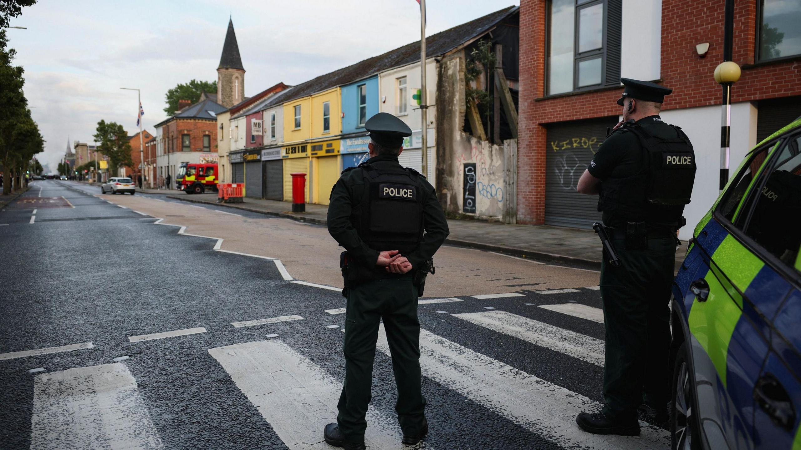 Two police officers stood on a zebra crossing