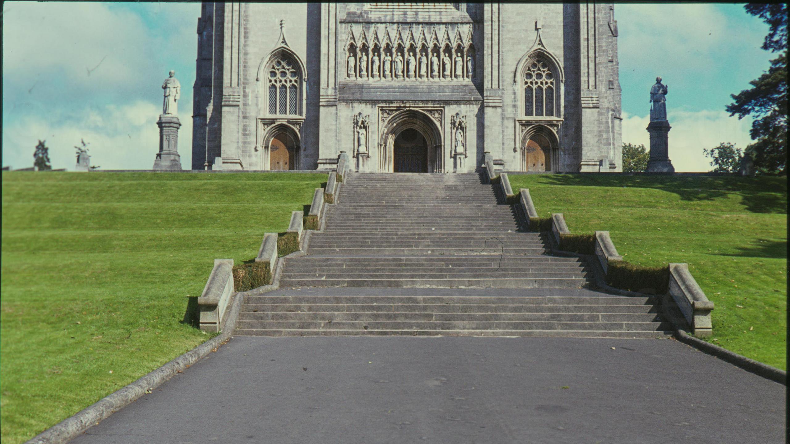 A digitalised photo from a film of stone steps leading to a large grey stone cathedral. 