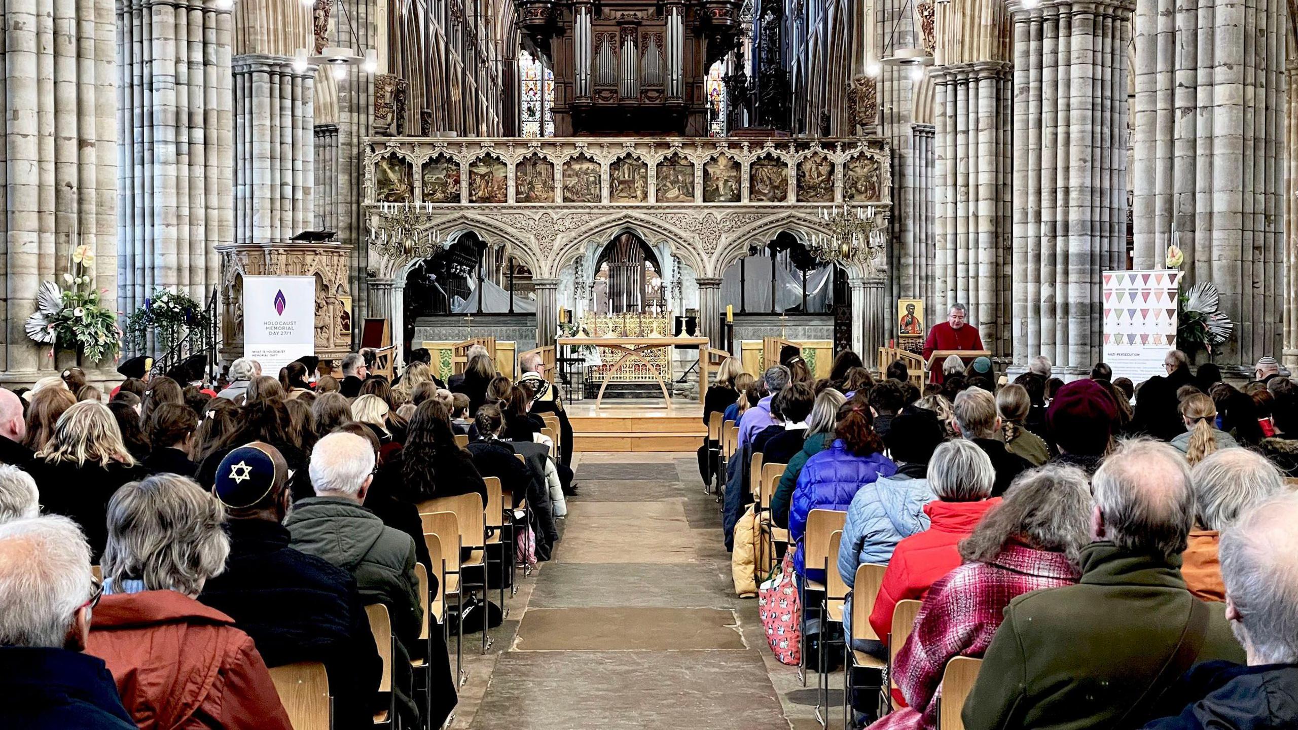 Rows of people sitting down and facing the front of a church. 