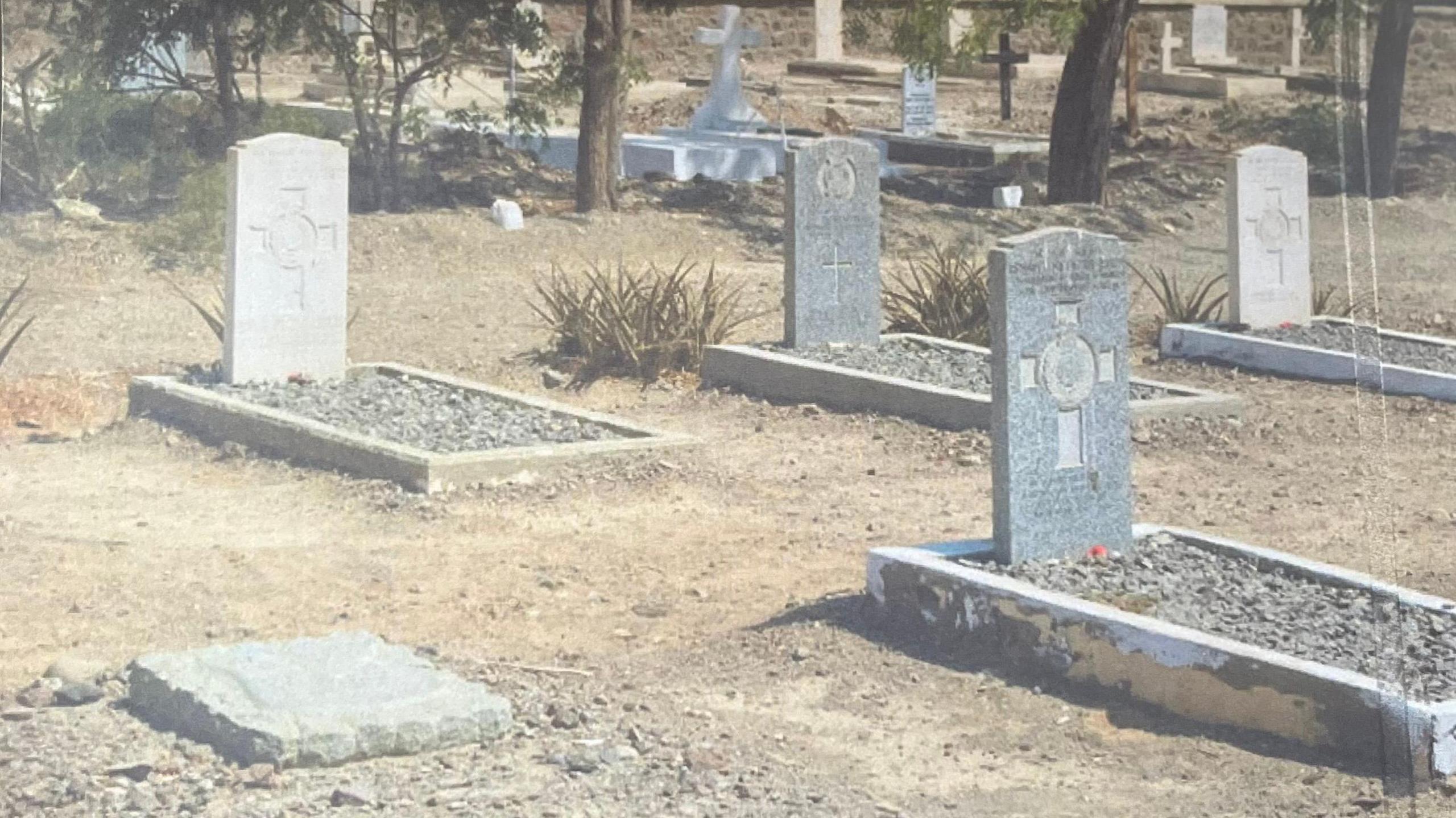 A faded photo of gravestones standing in parched earth in Yemen.
