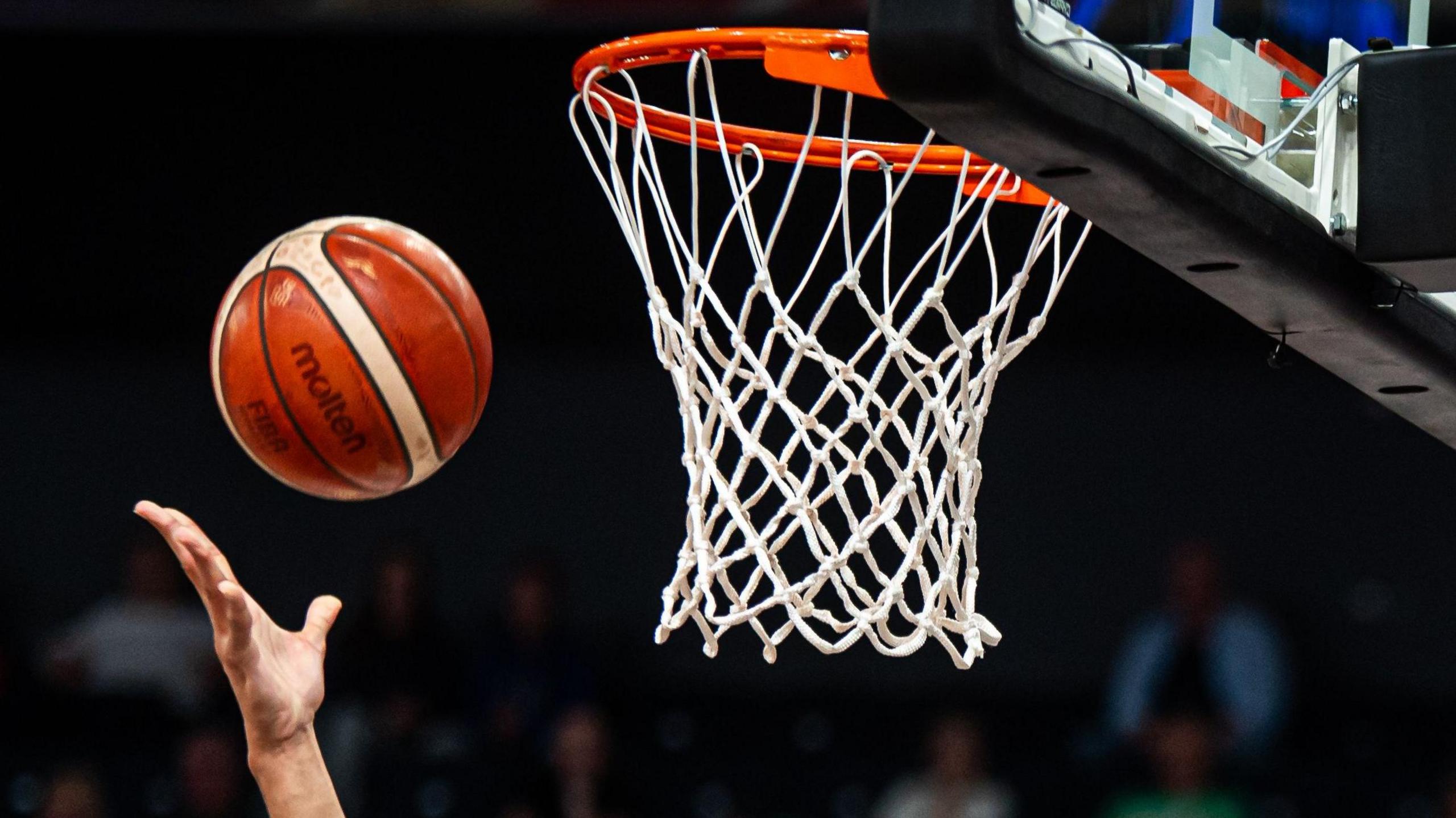 A basketball is thrown towards a net