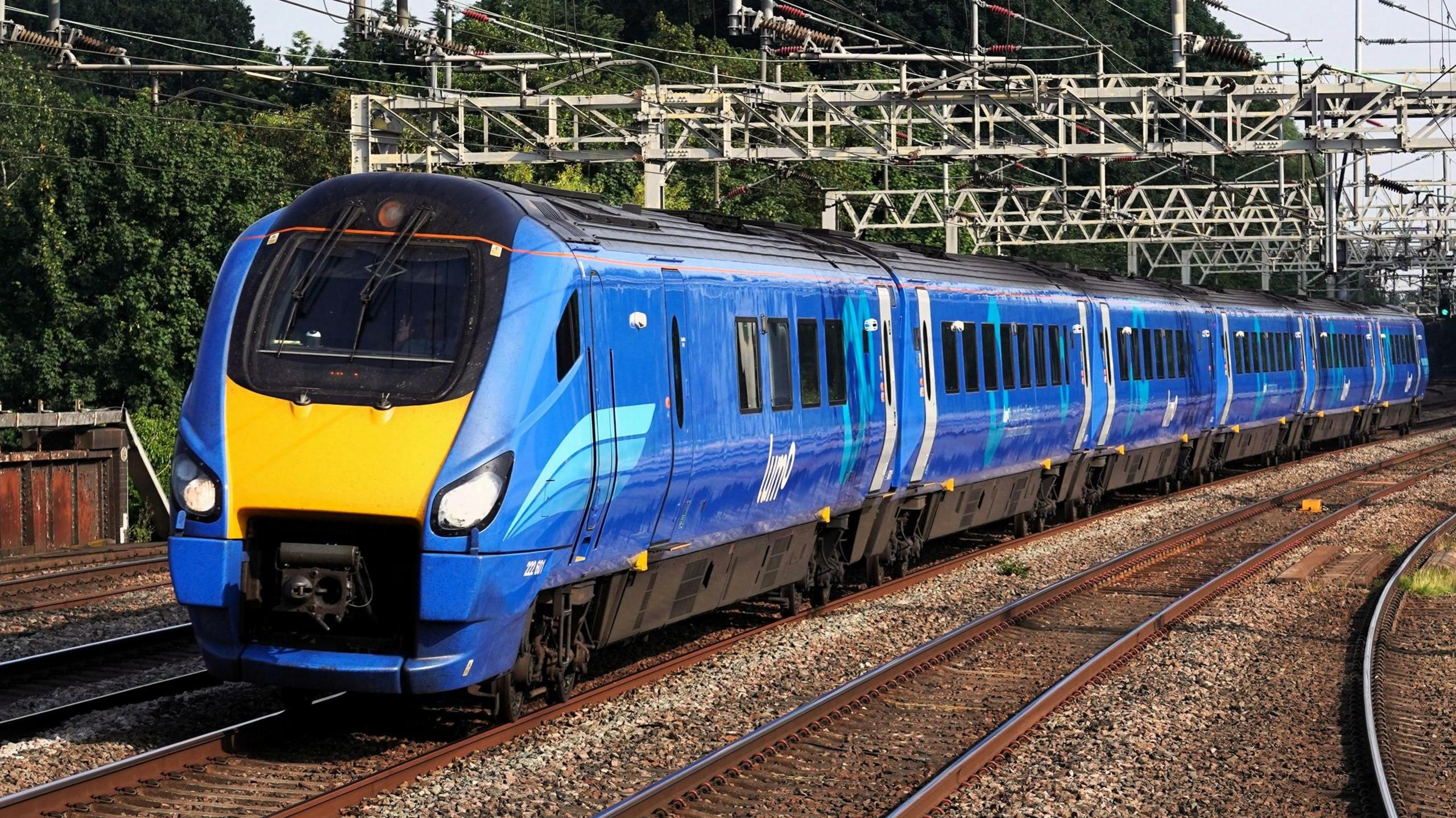 A blue train with Lumo branding travelling under overhead wires.