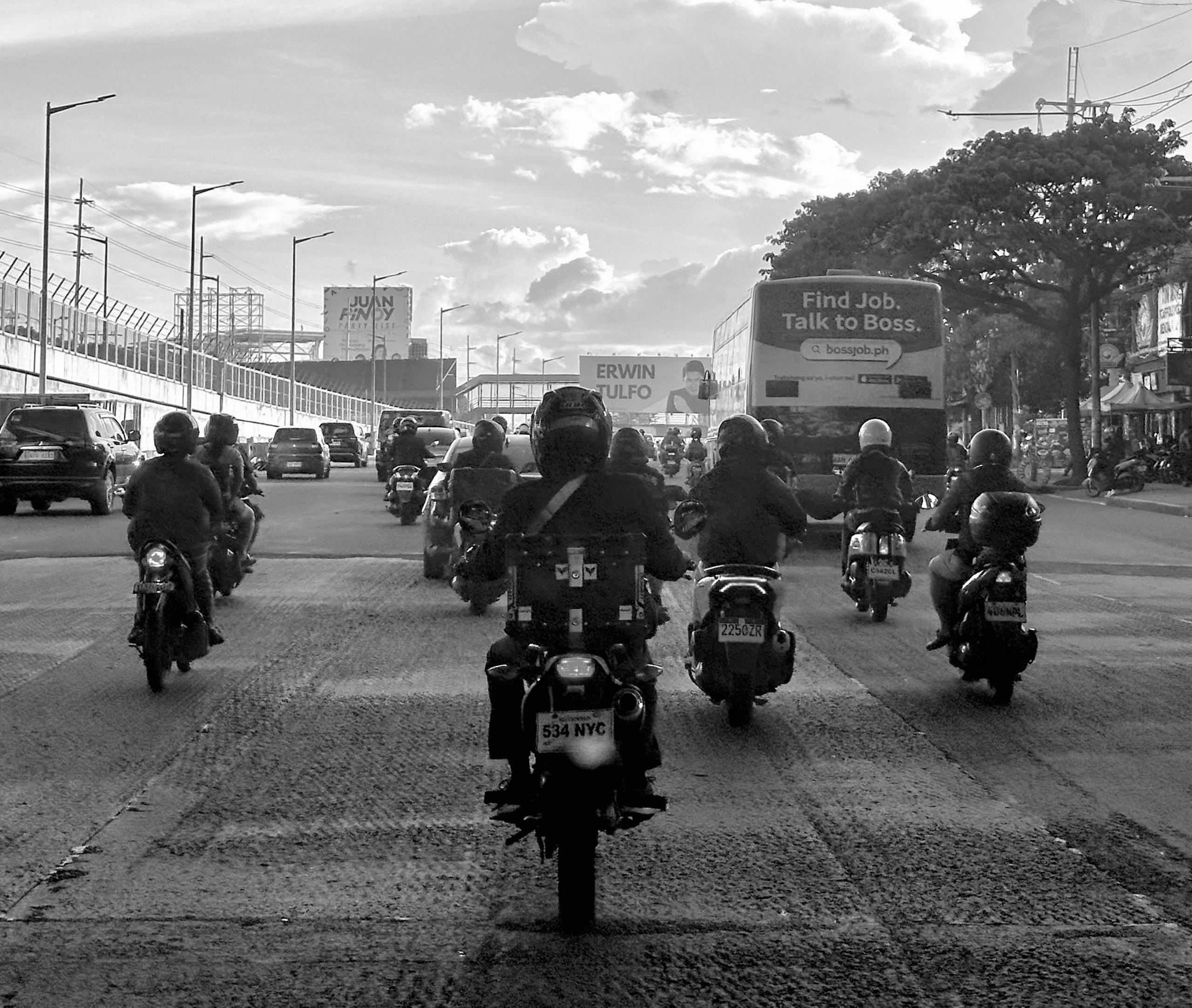 Motorbikes seen from behind on a wide road passing through a city