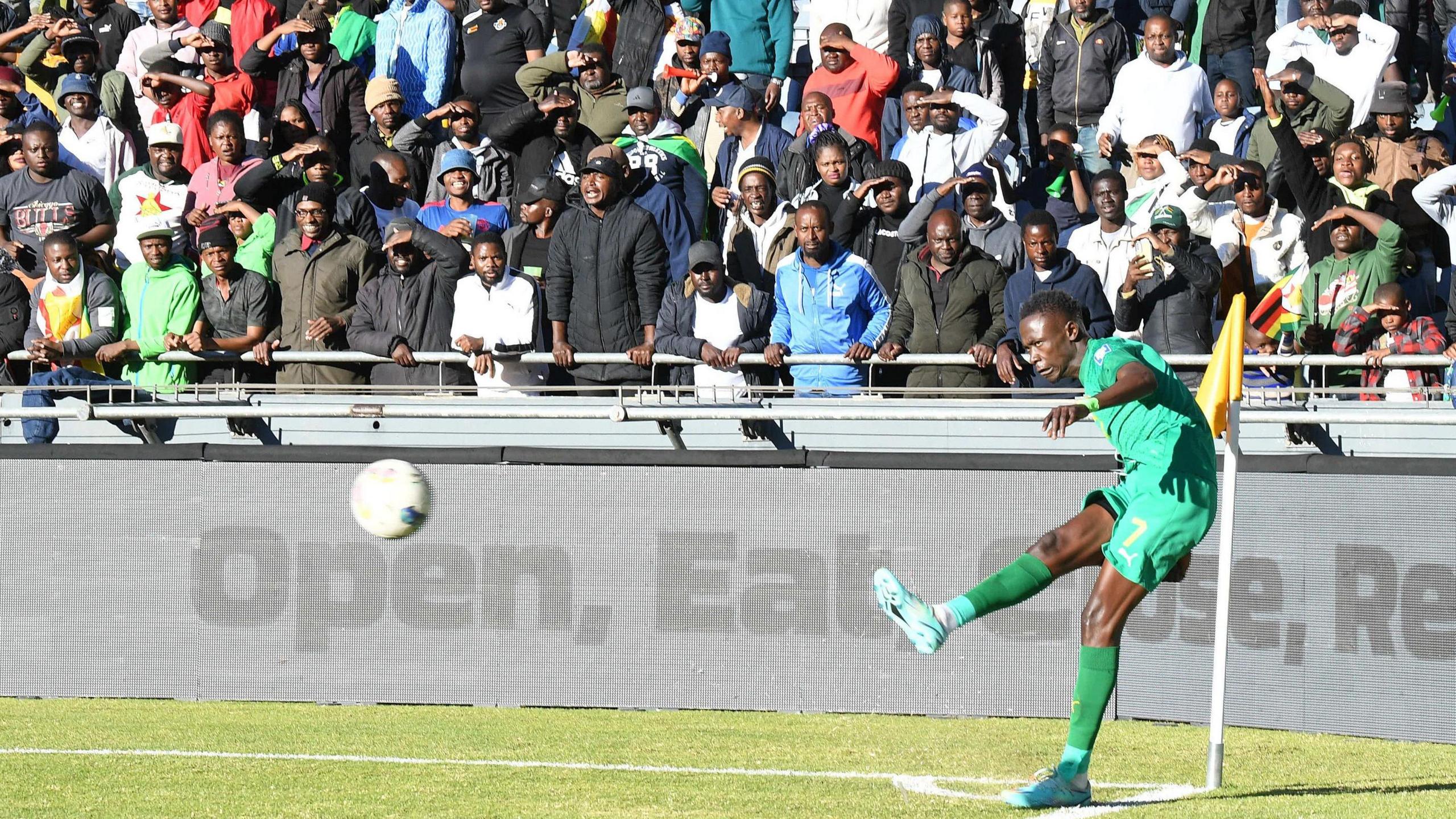 Andrew Mbeba of Zimbabwe during the 2026 World Cup qualifier against Lesotho at Orlando Stadium as fans in the background shield their eyes from the sun