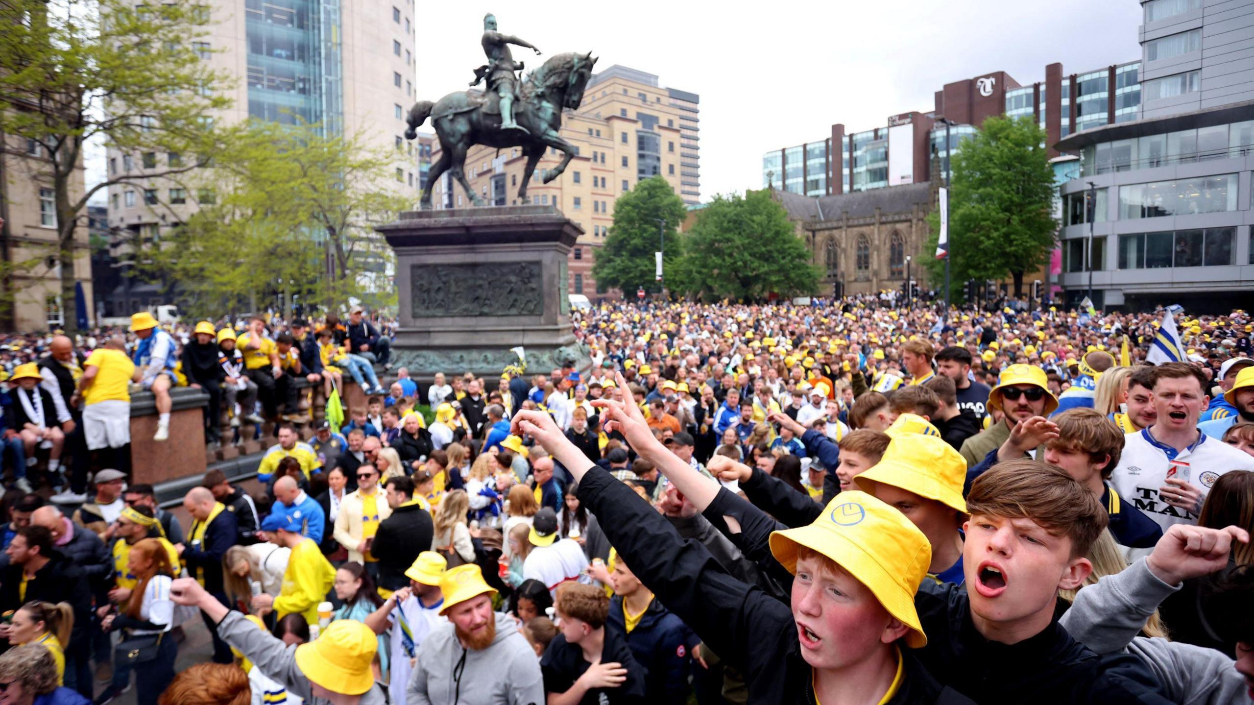 A sea of fans, many wearing yellow Leeds United bucket hats 