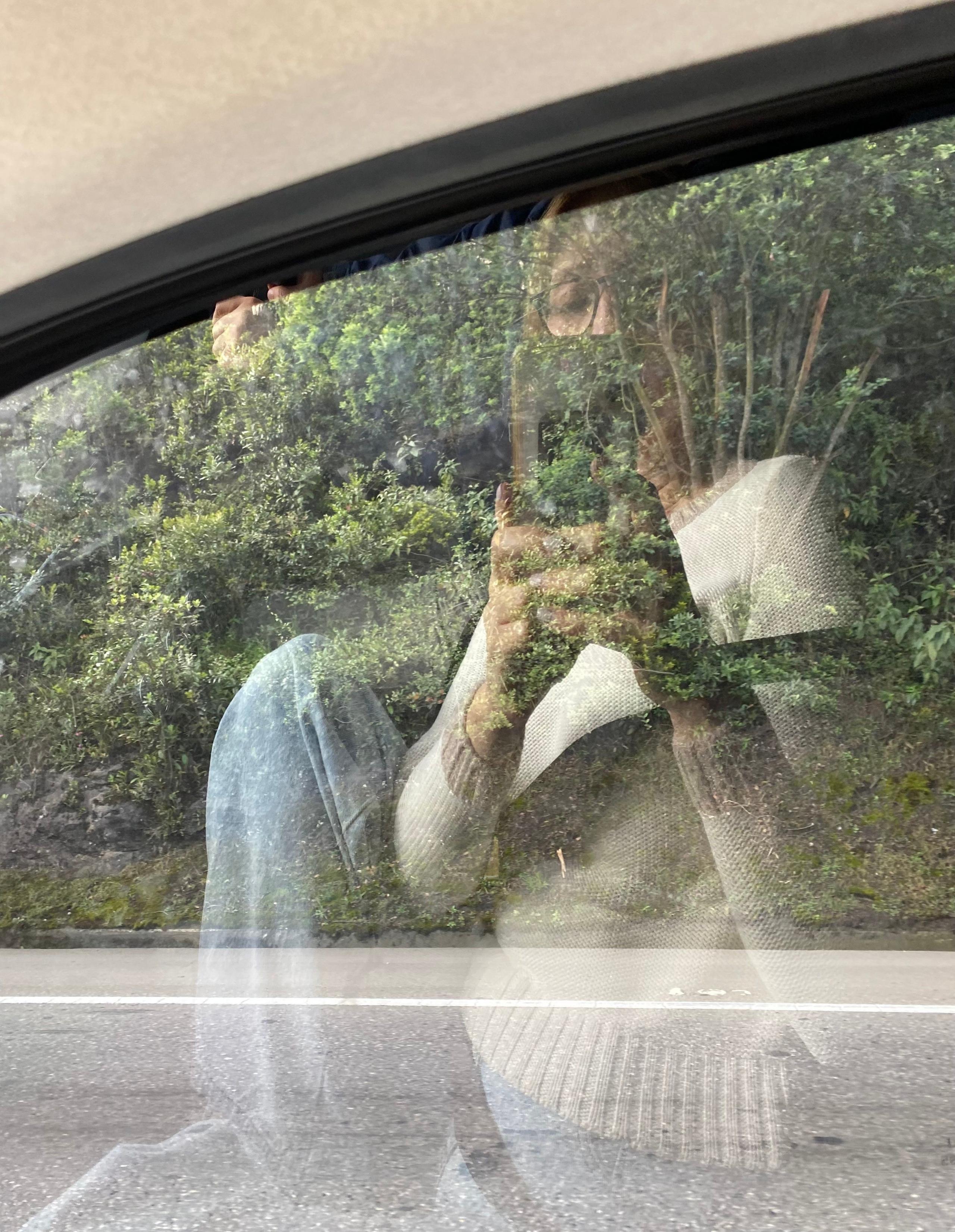 A woman takes a selfie in the window of car