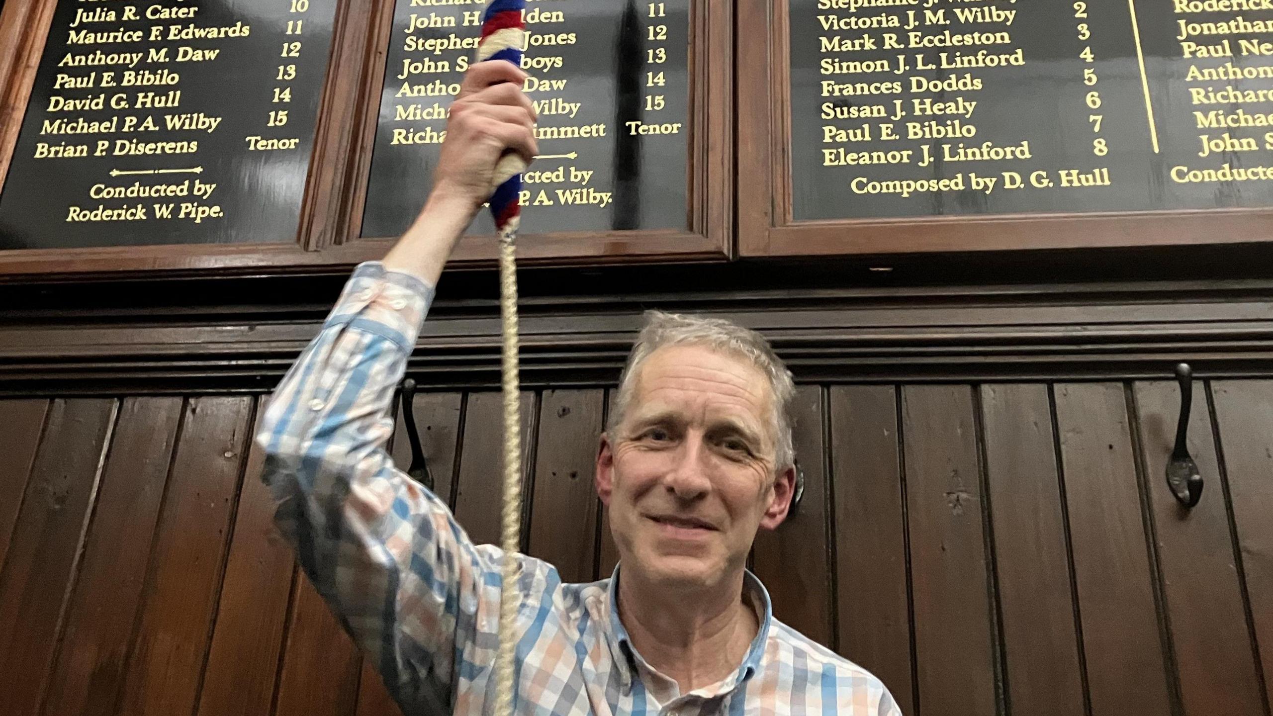 Simon Linford looking straight at the camera holding a bell rope.