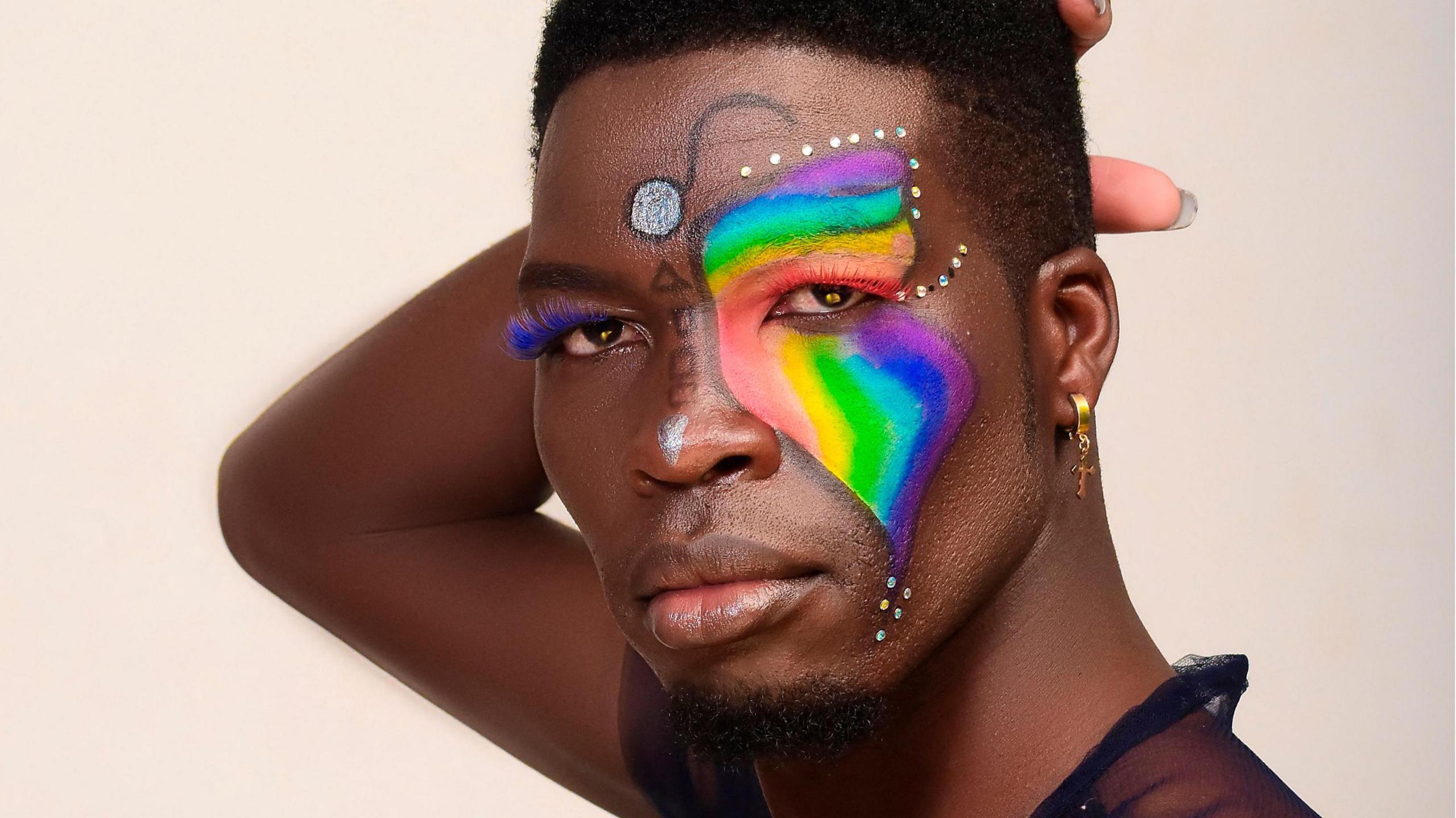 Edwin Chiloba, with an LGBTQ pride flag painted on the right half of his face, poses for a portrait at a studio in Eldoret on June 6, 2022.