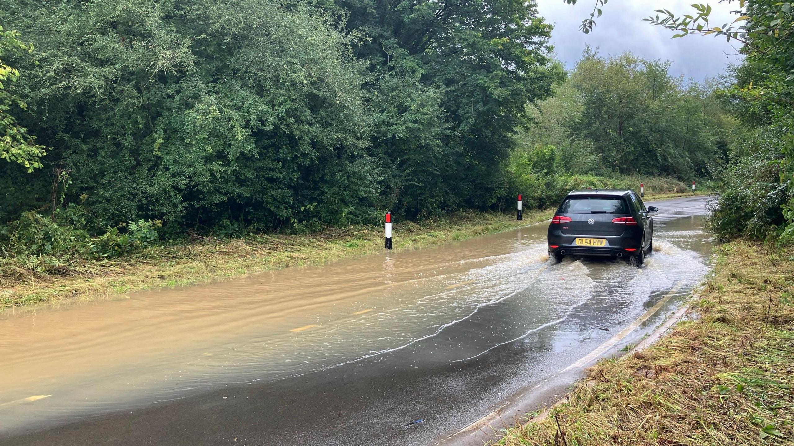 A car drives through flooding on a road