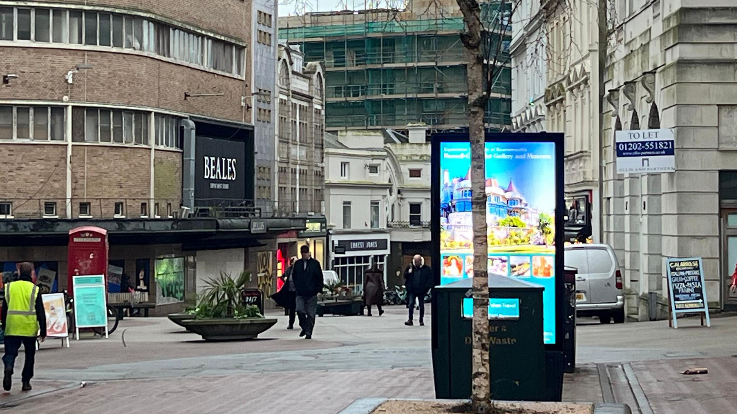 A high street with empty shops and people walking up and down the street. 