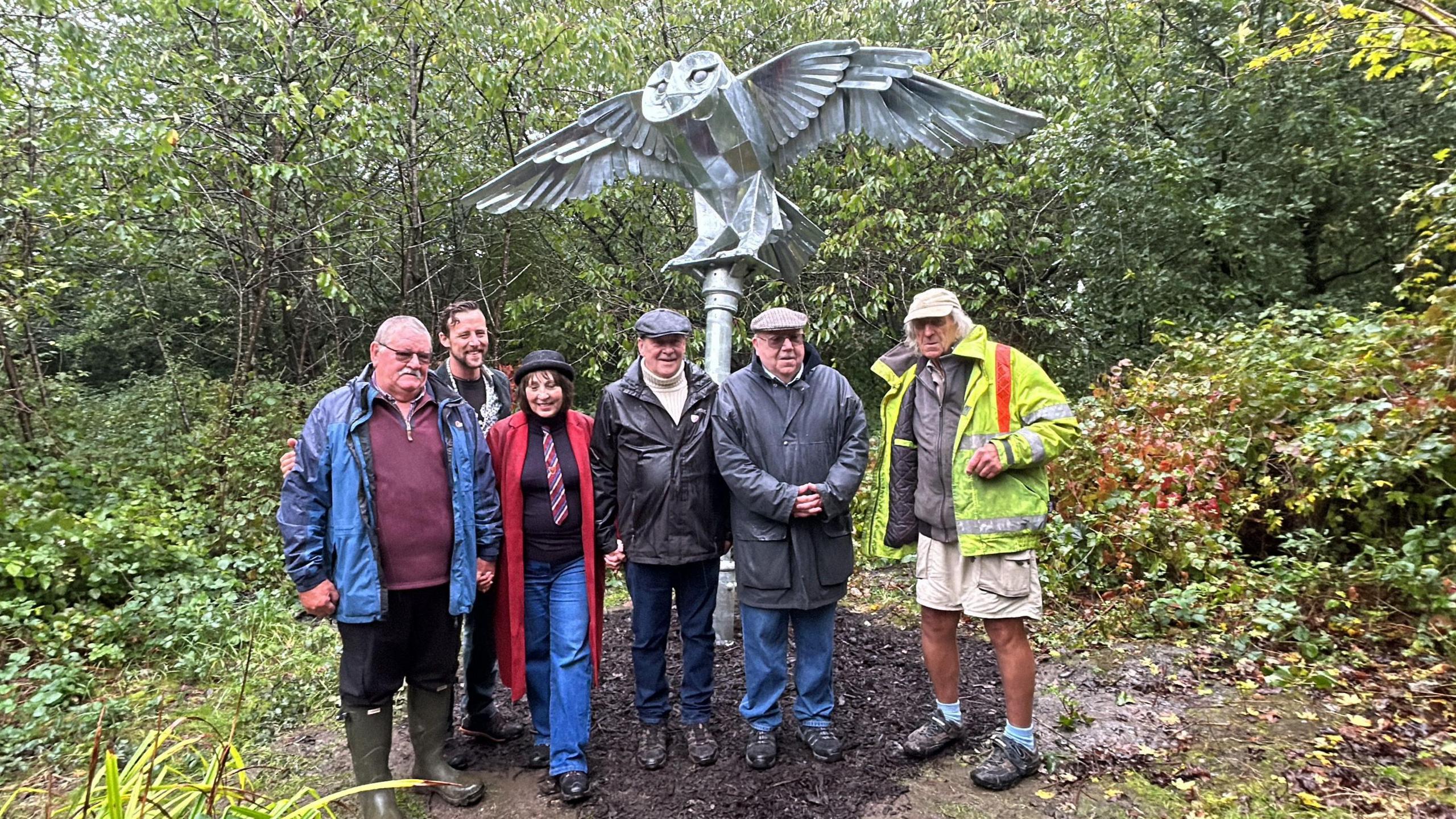 Ex-pupils and members of the Forever Churchfields group, along with sculptor Luke Perry and old teacher Bill Whitehead, stand next to the new owl monument in Sandwell Nature Valley. Bill Whitehead wears a high-vis jacket.