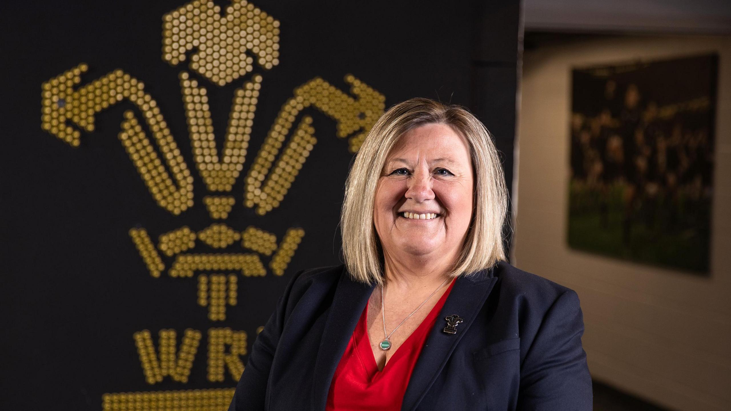Nadine Griffiths stand in front of WRU badge
