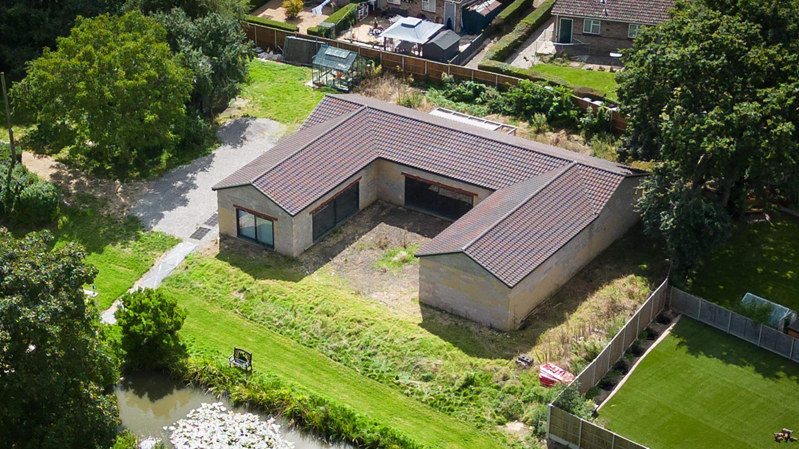 The 'Captain Tom Foundation building' that was built beside the Ingram-Moores' home. It is a birds eye view photo. A green lawn and river are visible.