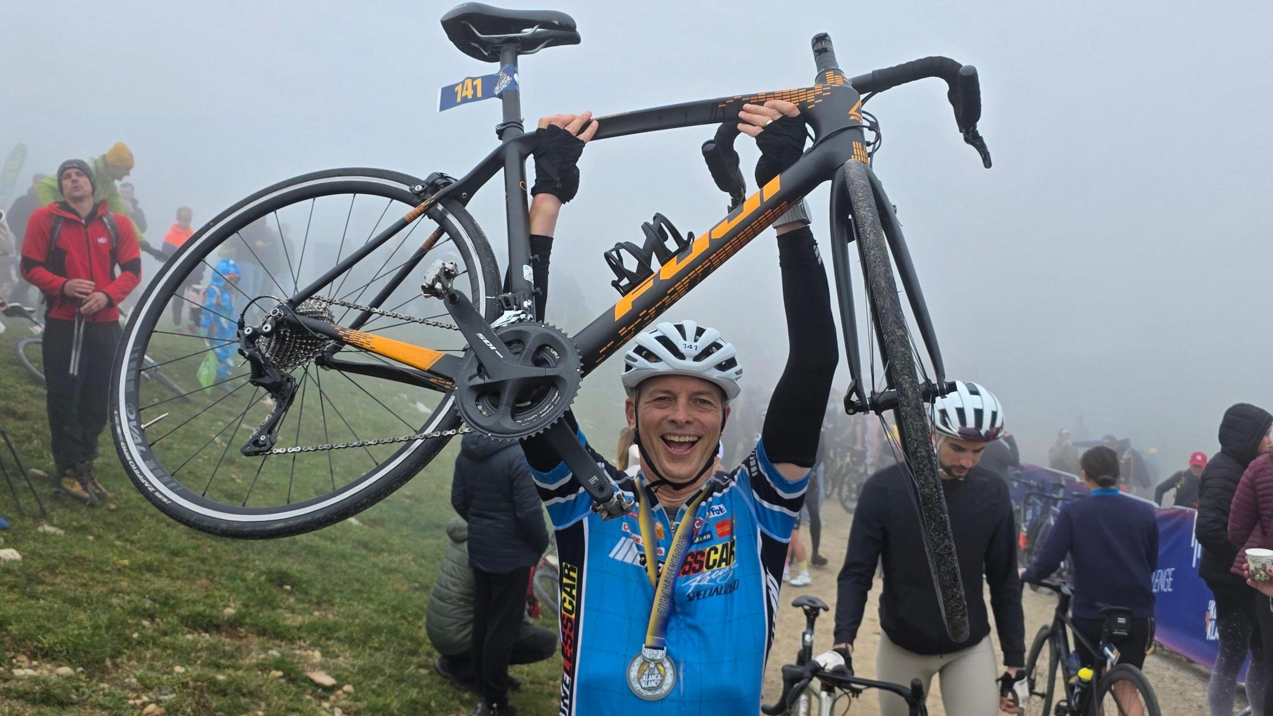 Guy Delauney raises his bike in the air