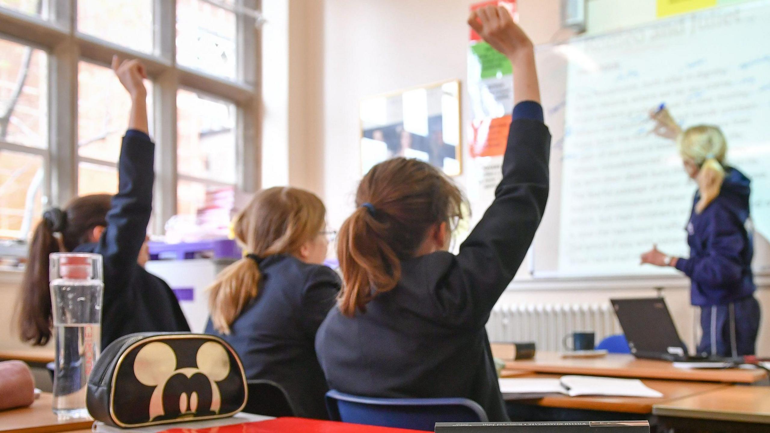 Children with hands up in classroom