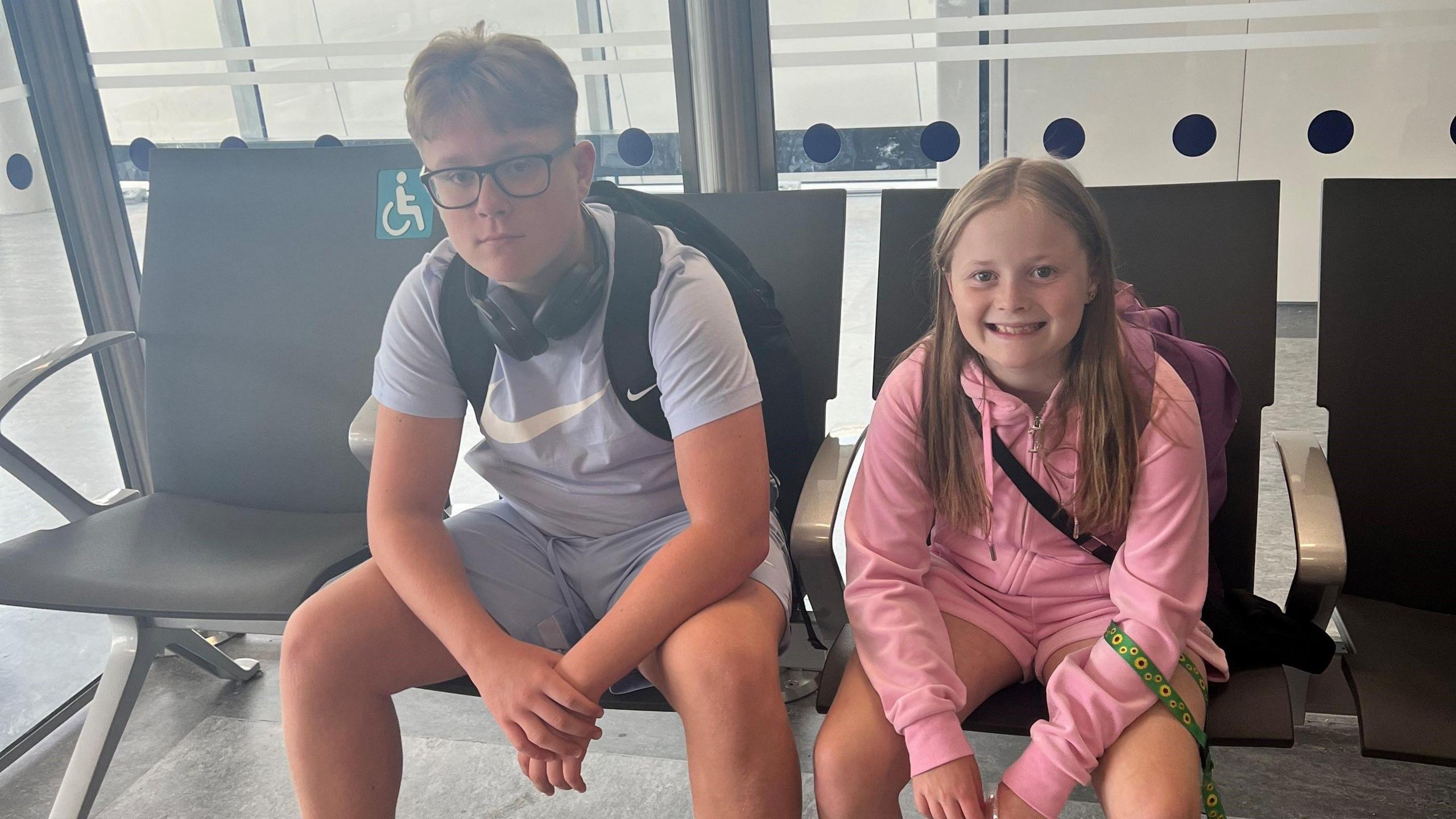 Two children sitting on seats at an airport