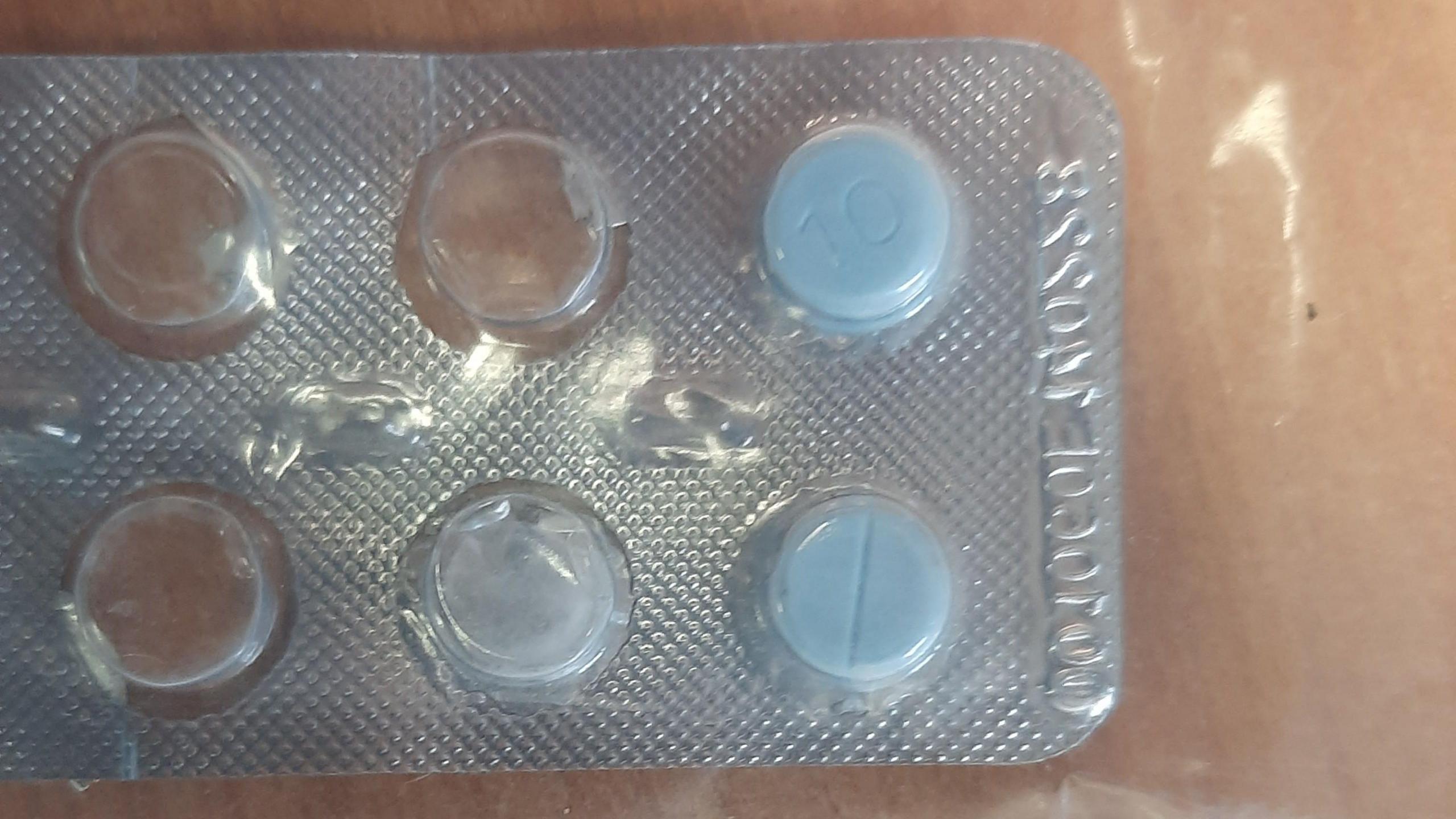 Two light blue pills in a blister pack. One of the pills has a line indented in it and the other has the number 10 on it.