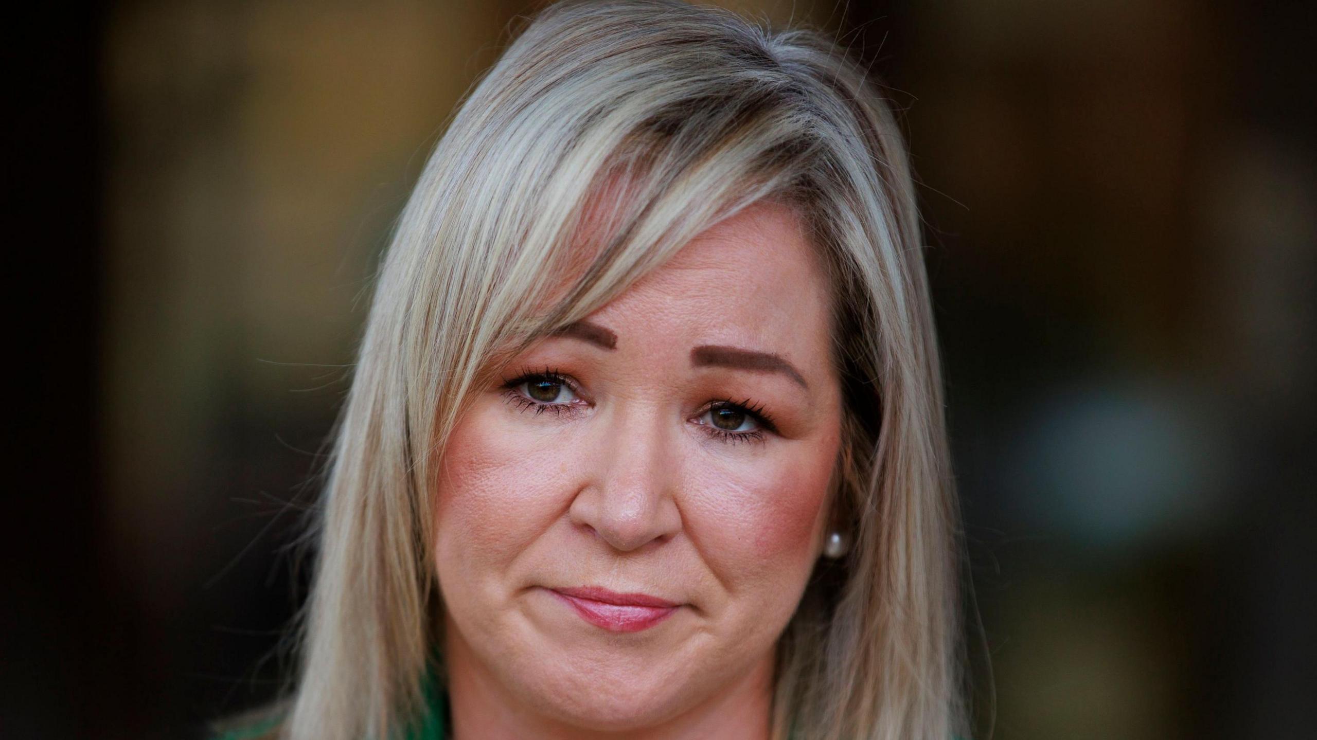 A close-up picture of Michelle O'Neill who has blonde hair and is wearing lipstick. She is frowning.