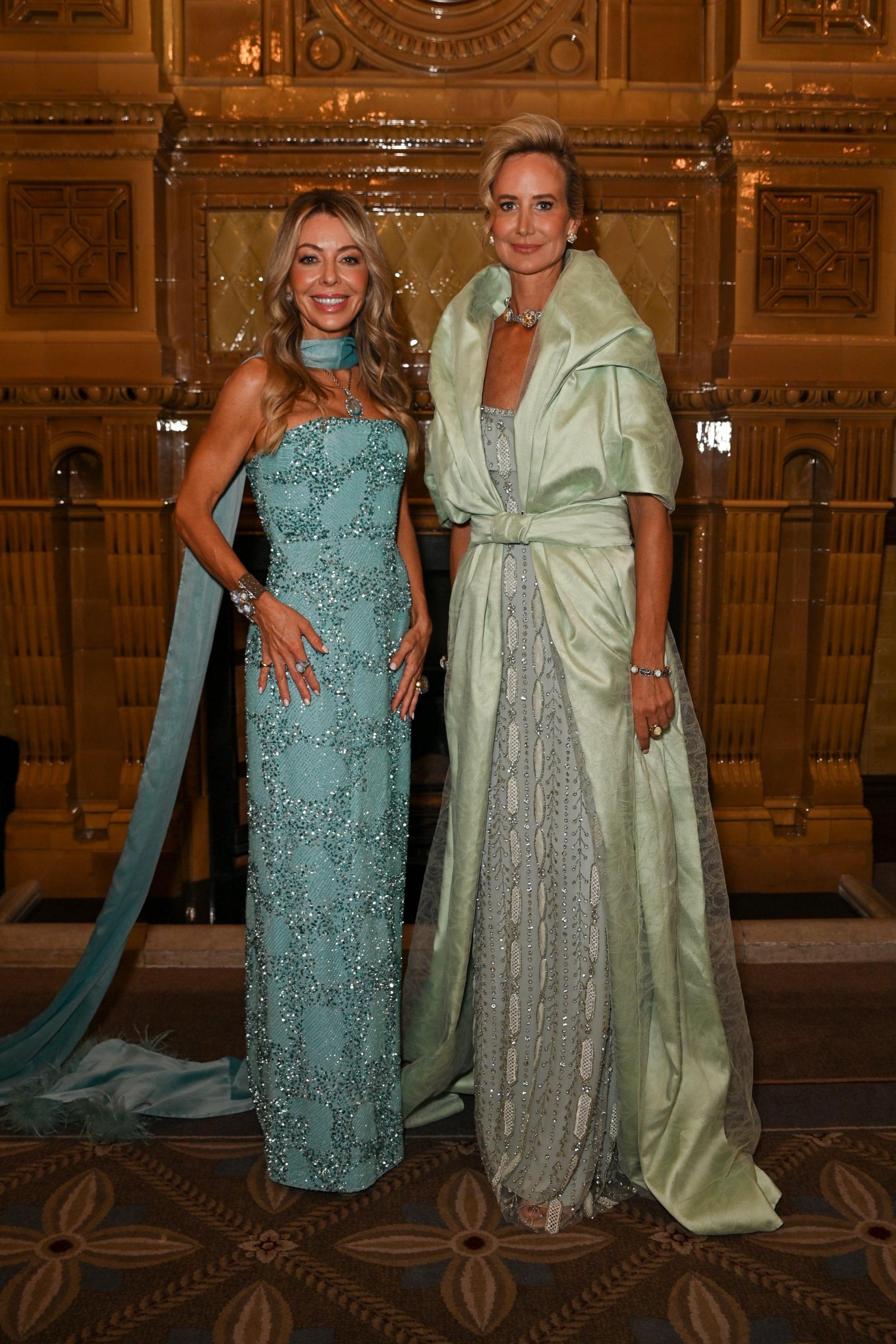 Juliet Mayhew is wearing a striking blue evening gown with neck scarf and Lady Victoria Hervey wears a sage green evening dress.