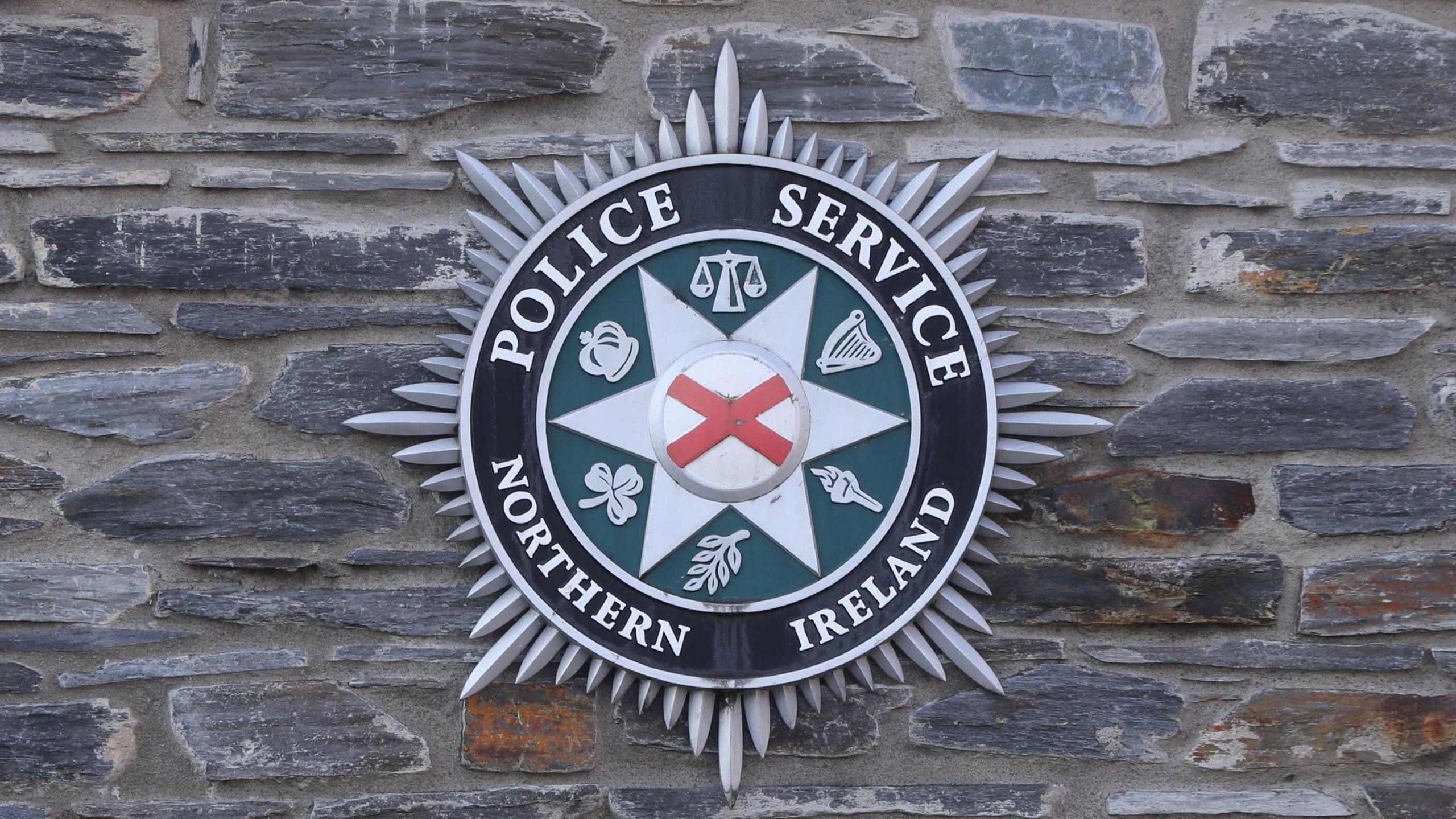A PSNI logo on a grey brick wall