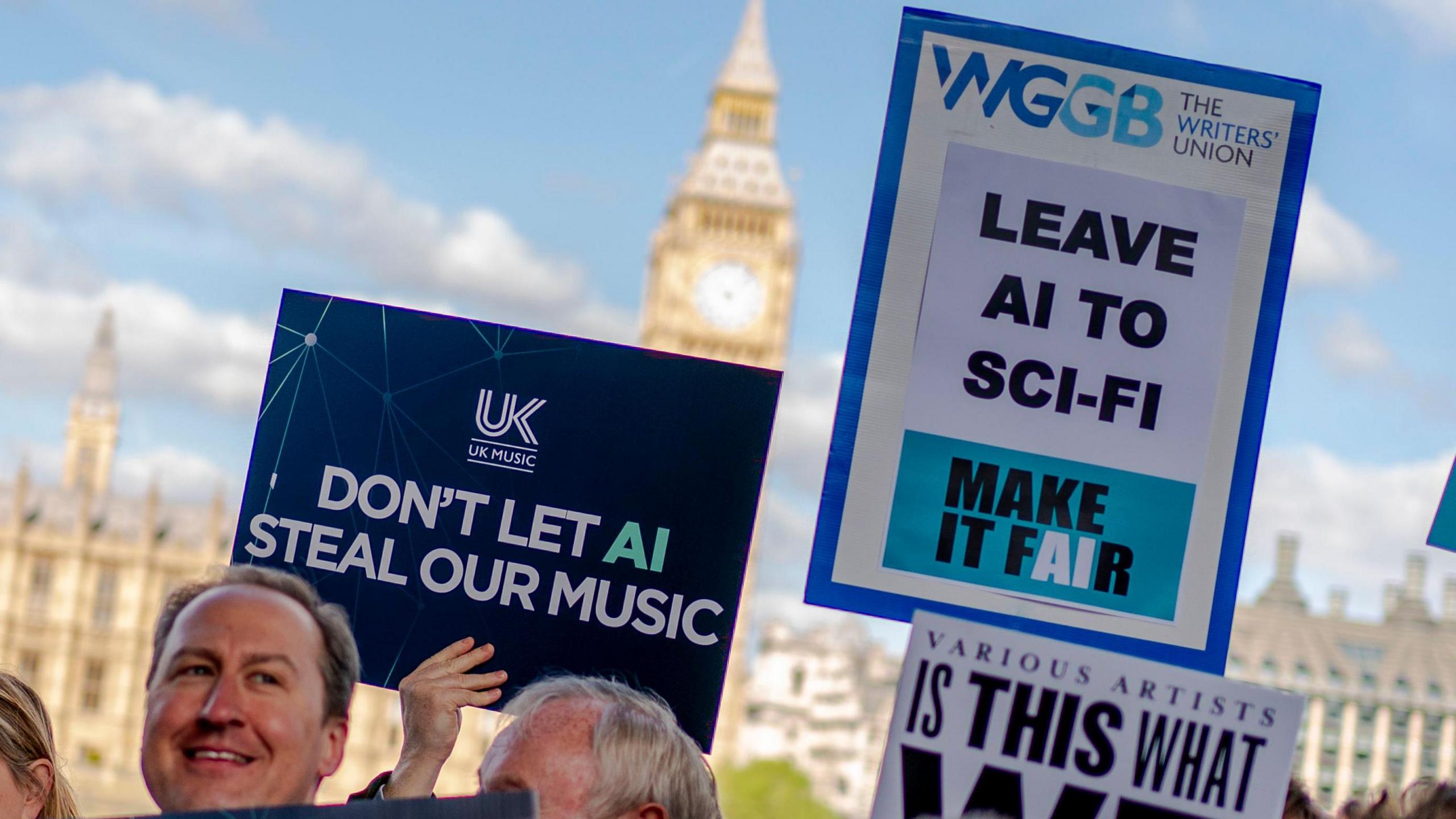 Creatives in the music industry protest outside UK Parliament. A dark blue placard from trade association UK Music reads: "Don't let AI steal our music". Another beside it, from The Writer's Union, says: "Leave AI to sci-fi". 
