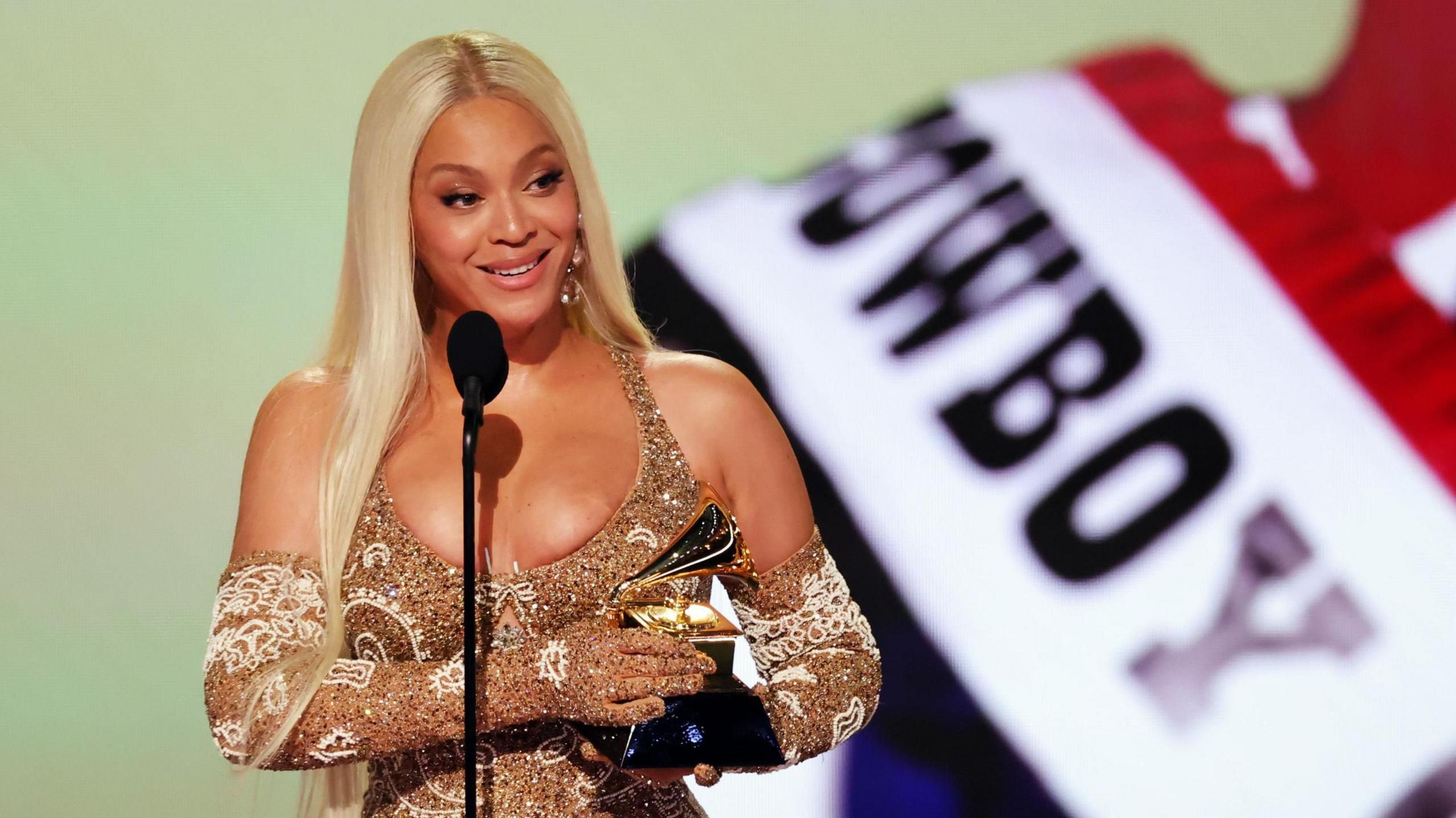 Beyoncé holds her award on stage at the Grammys