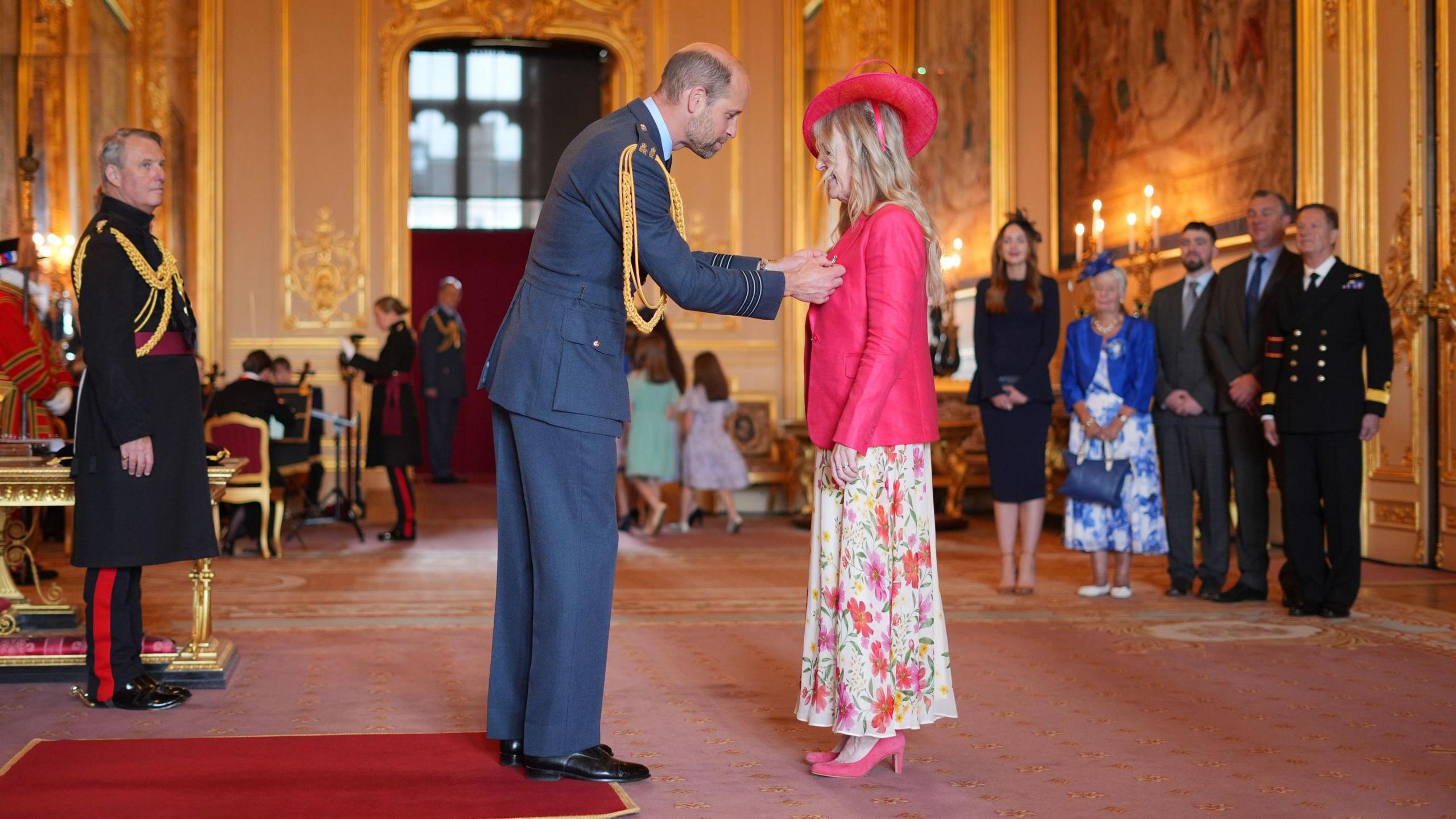 The Prince of Wales presents Dawn Astle with her MBE medal as her family look on