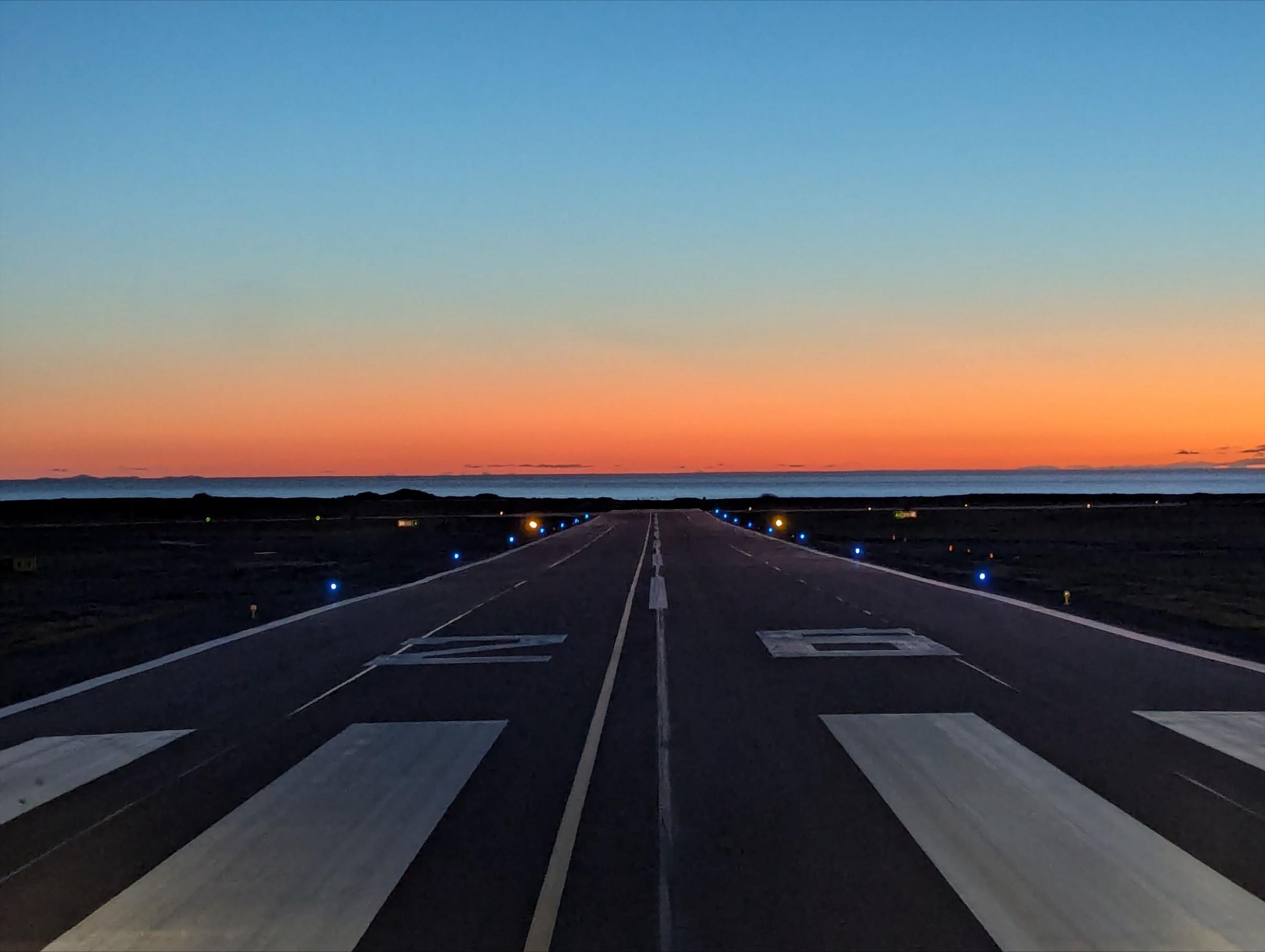 A sunset over the runway of an airport runway.