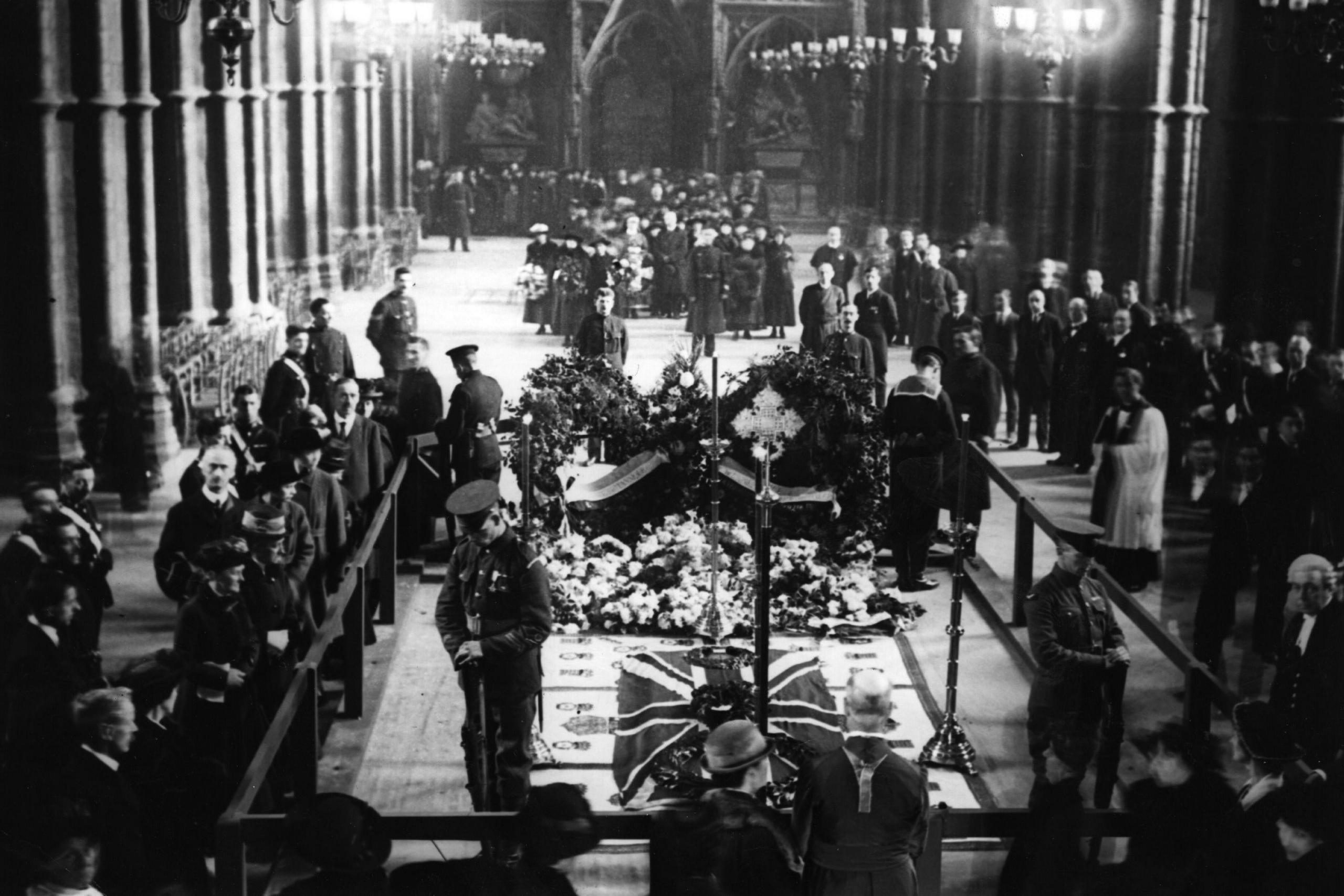 Soldiers and mourners surround the tomb of the unknown warrior lying in state in Westminster Abbey following his burial in 1922