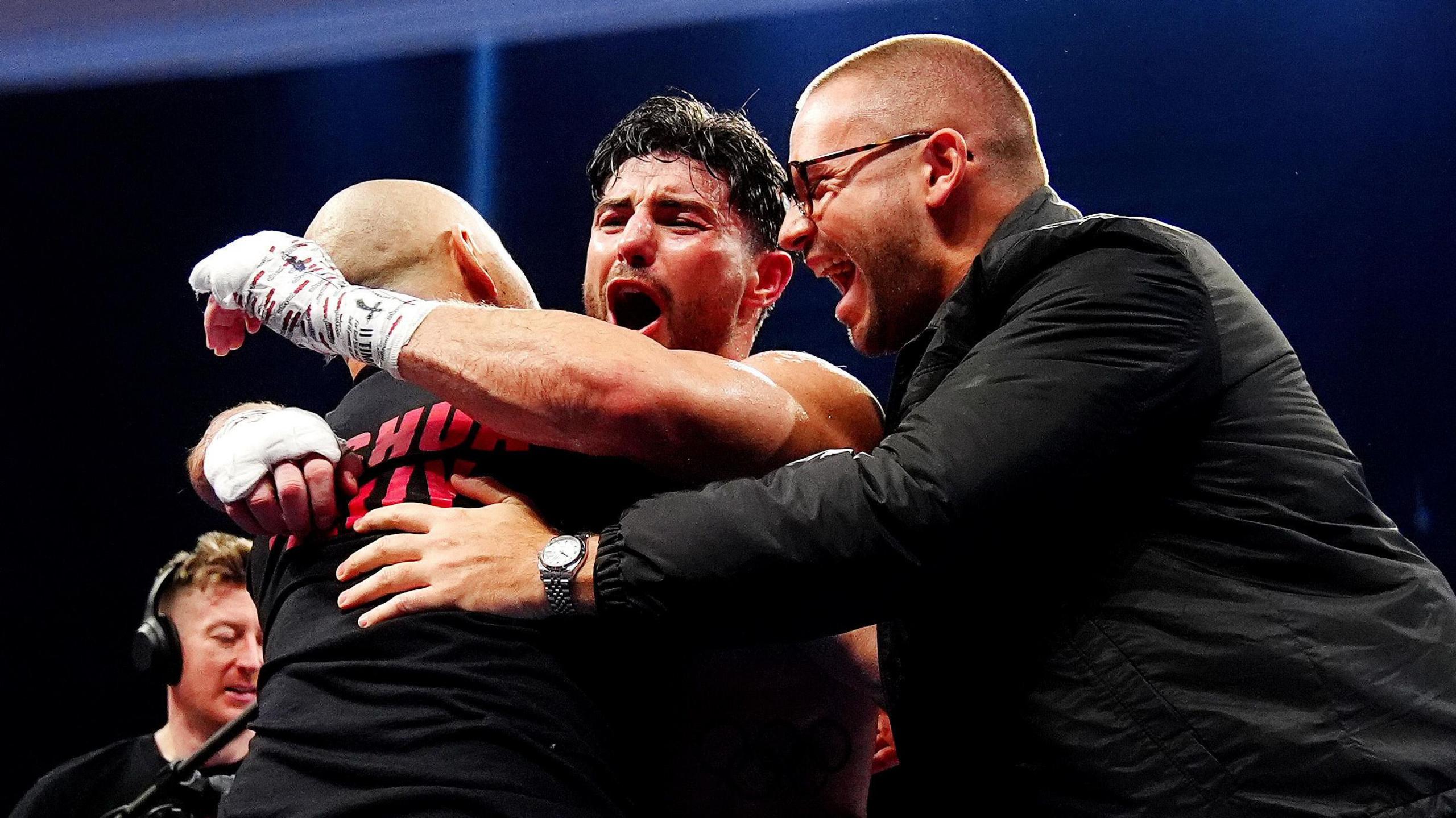 Josh Kelly hugs Adam Booth and Frank Smith