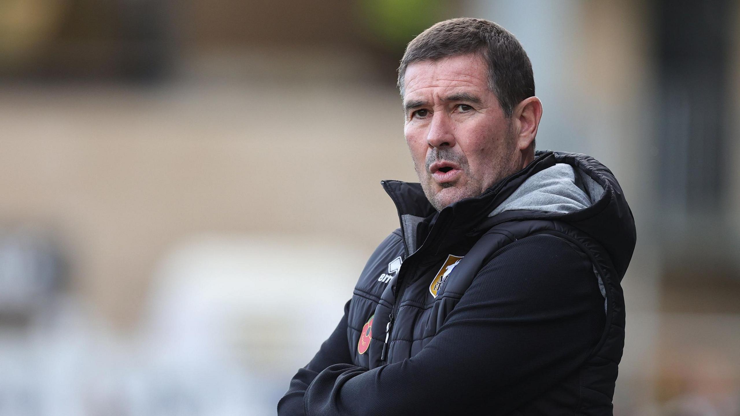 Mansfield boss Nigel Clough with his arms crossed on the sideline