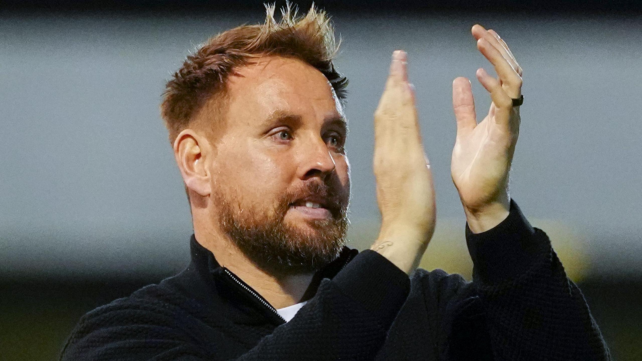 Crawley head coach Rob Elliot smiling and applauding