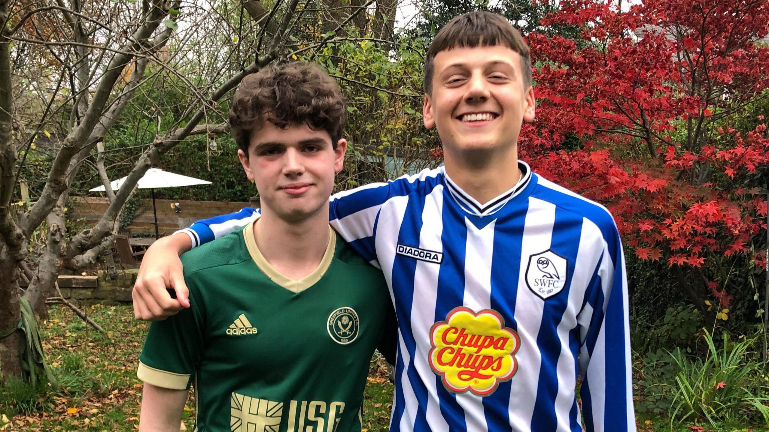 Ruben and Joe are stood with their arms around each other - Ruben is wearing a Sheffield Wednesday shirt, and Joe is wearing a Sheffield United shirt.