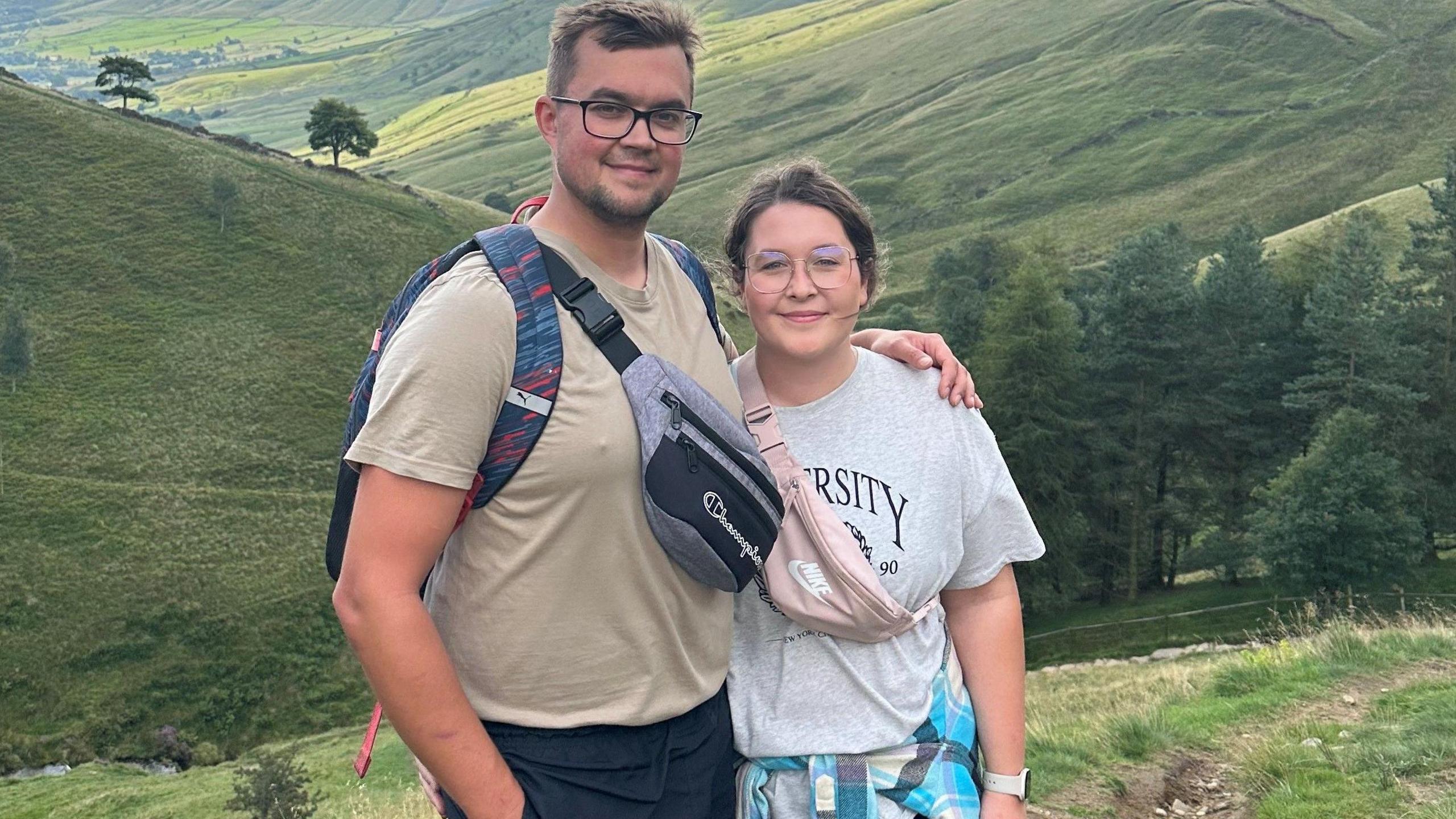 Aleksandra Wilińska with her husband Patrick. The couple are smiling for a photo taken in the Peak District with rolling hills in the background.