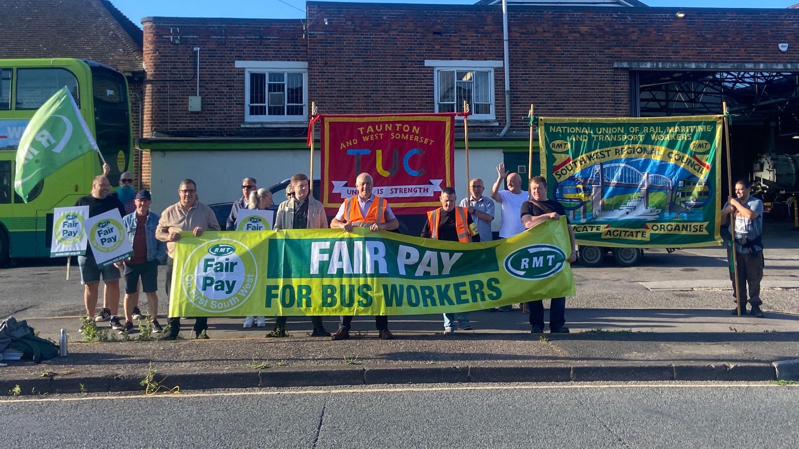 RMT Union members take strike action outside Taunton bus depot - they are holding a green banner that says 'Fair pay for bus workers'