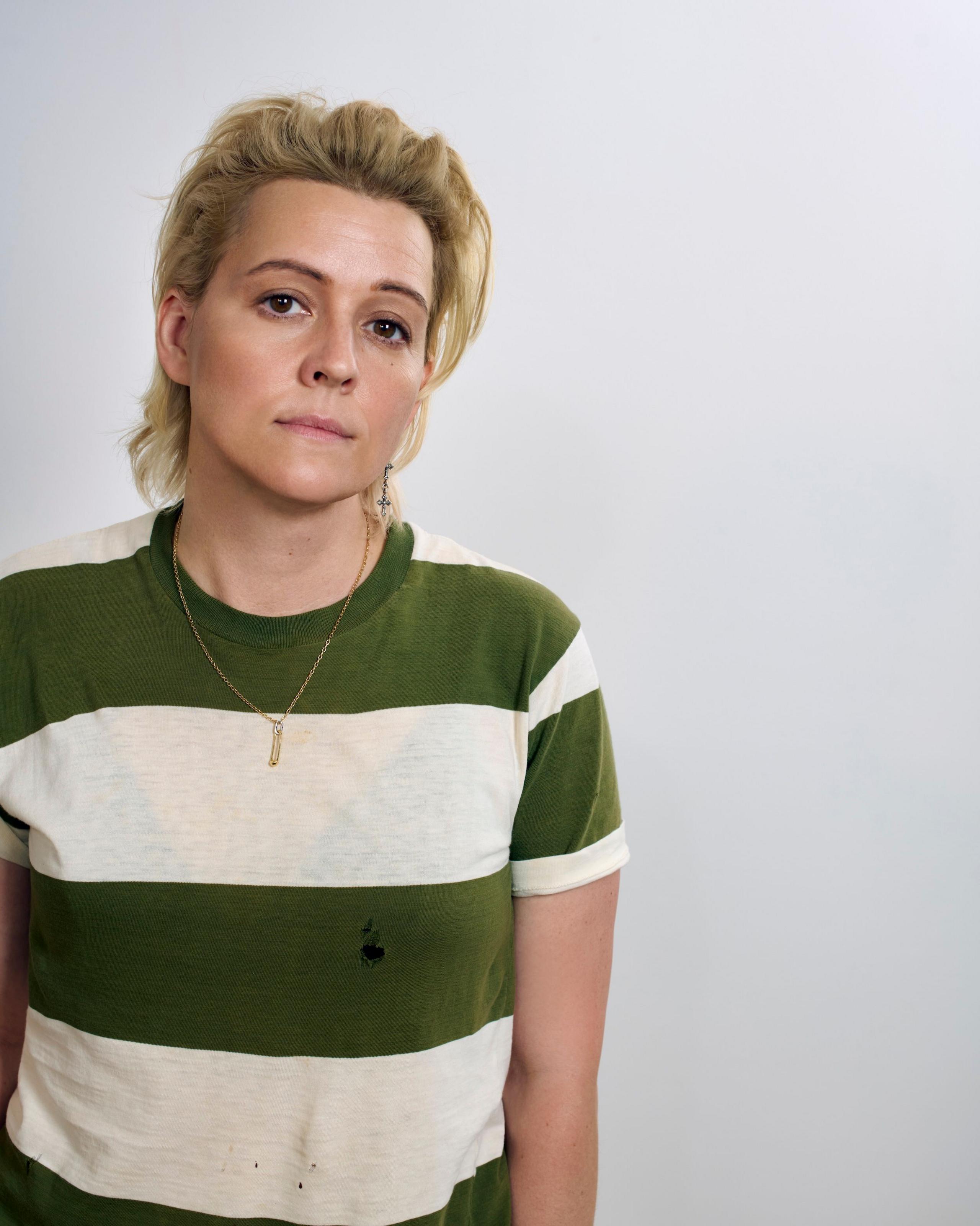 Brandi Carlile looks into the camera, while wearing a striped green and white top, in a promotional photo for her new album, Returning To Myself