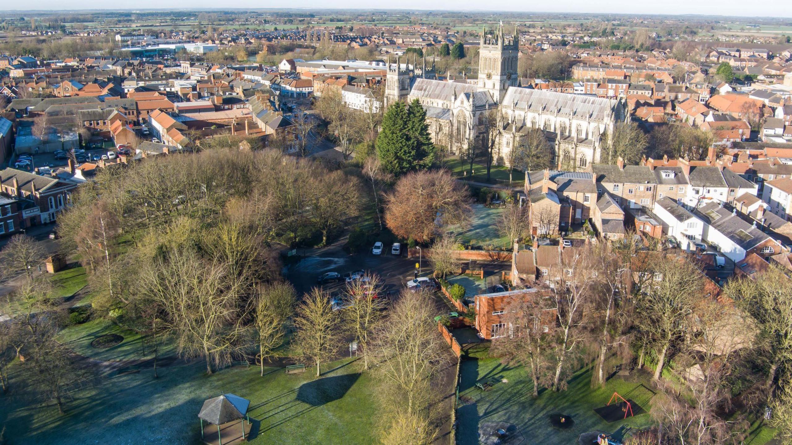 An aerial view of Selby Park, within which a bandstand and playground can be seen. In the background is Selby Abbey.