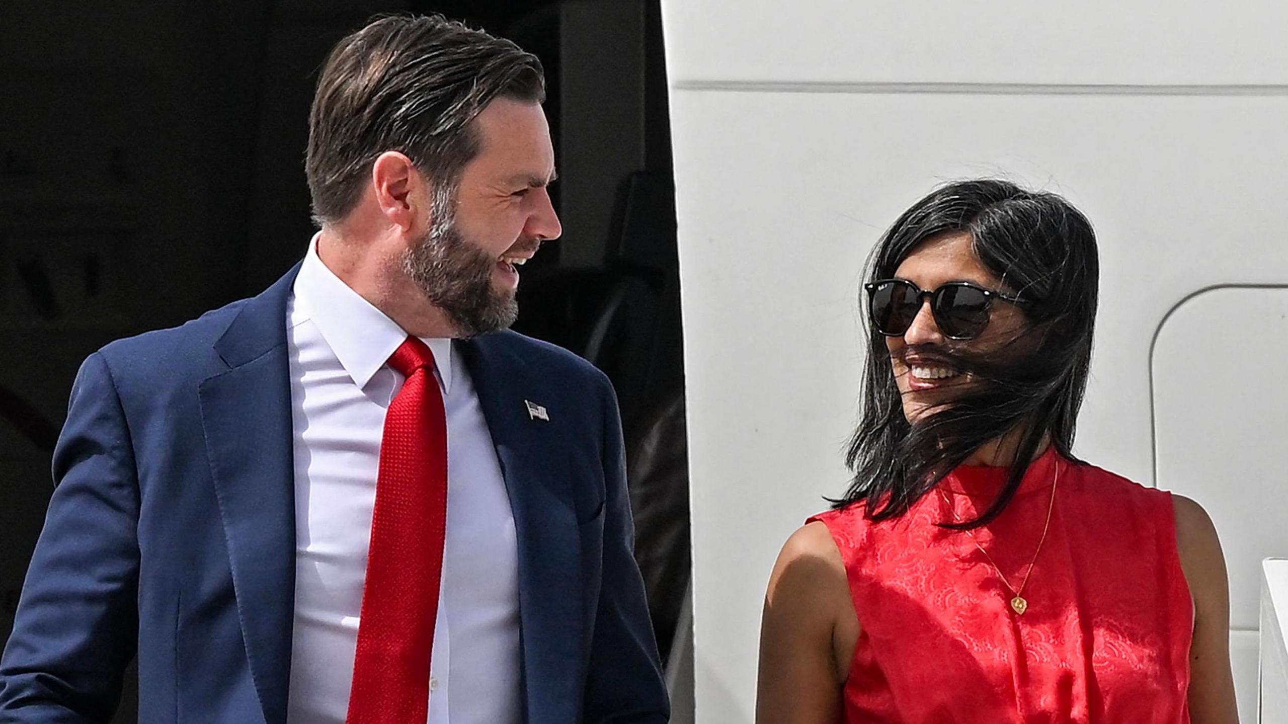 JD Vance and his wife Usha Vance disembark from an aircraft and smile at each other