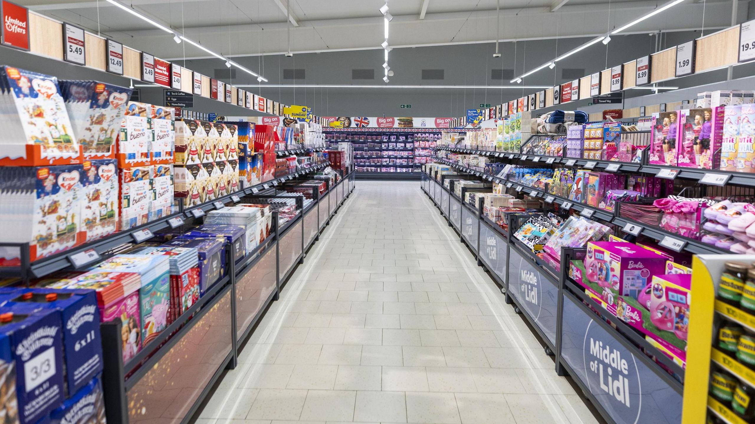 A view of the middle aisle of Lidl with shelves and baskets of products including toys and advent calendars