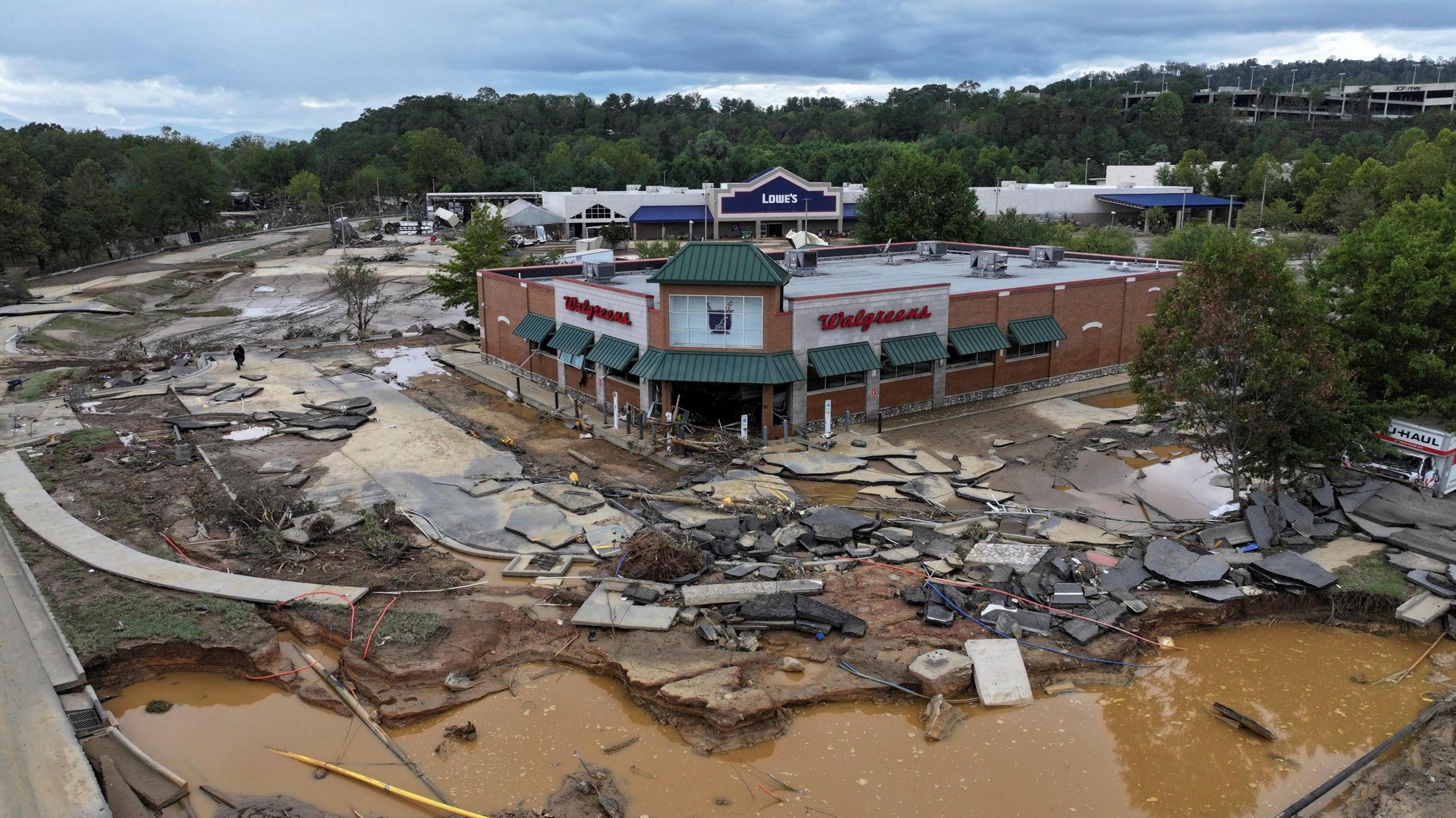 Debris, broken paving and flood water surrounding a damaged supermarket