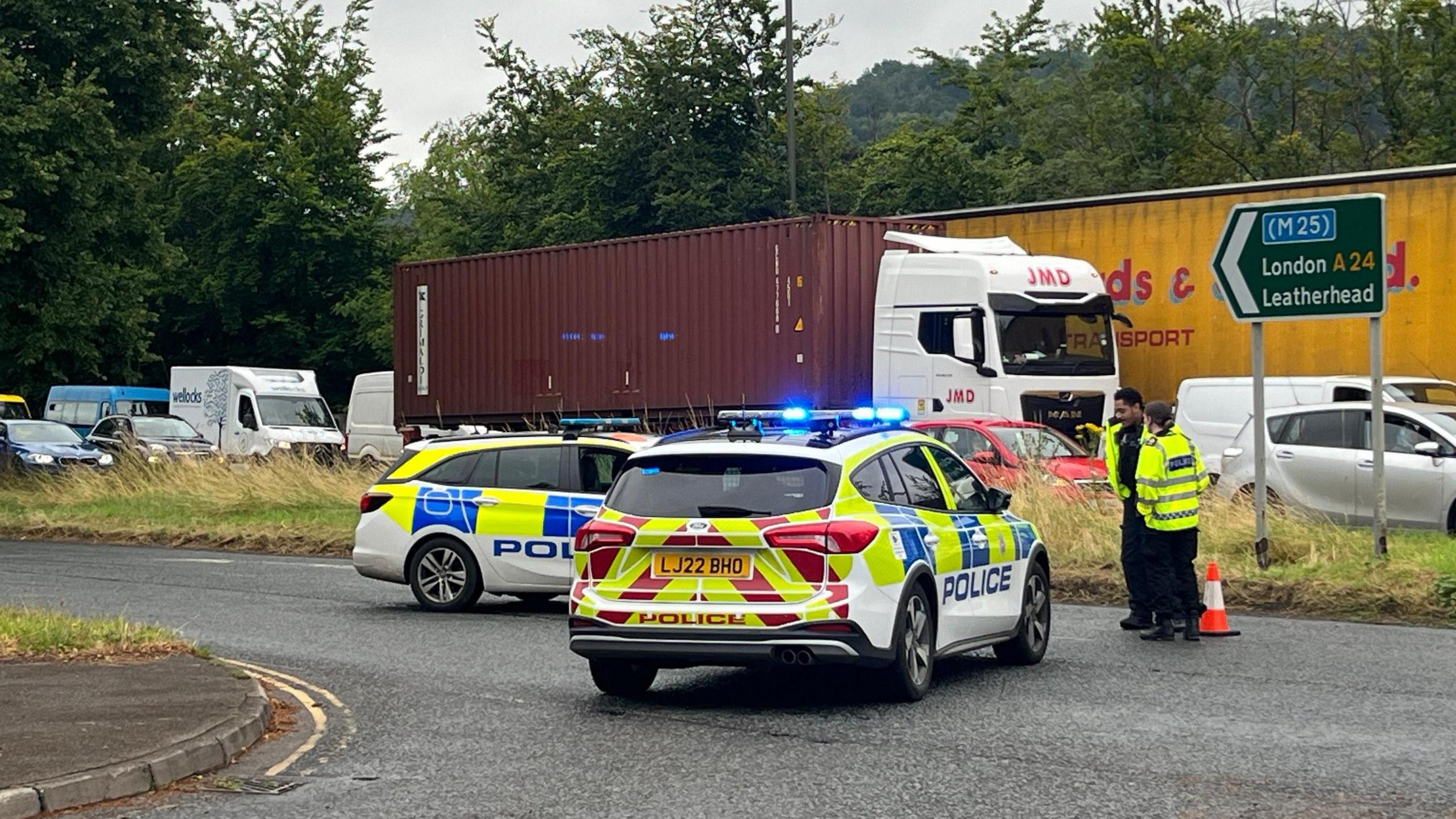 Police cars and queuing traffic with a sign for the M25