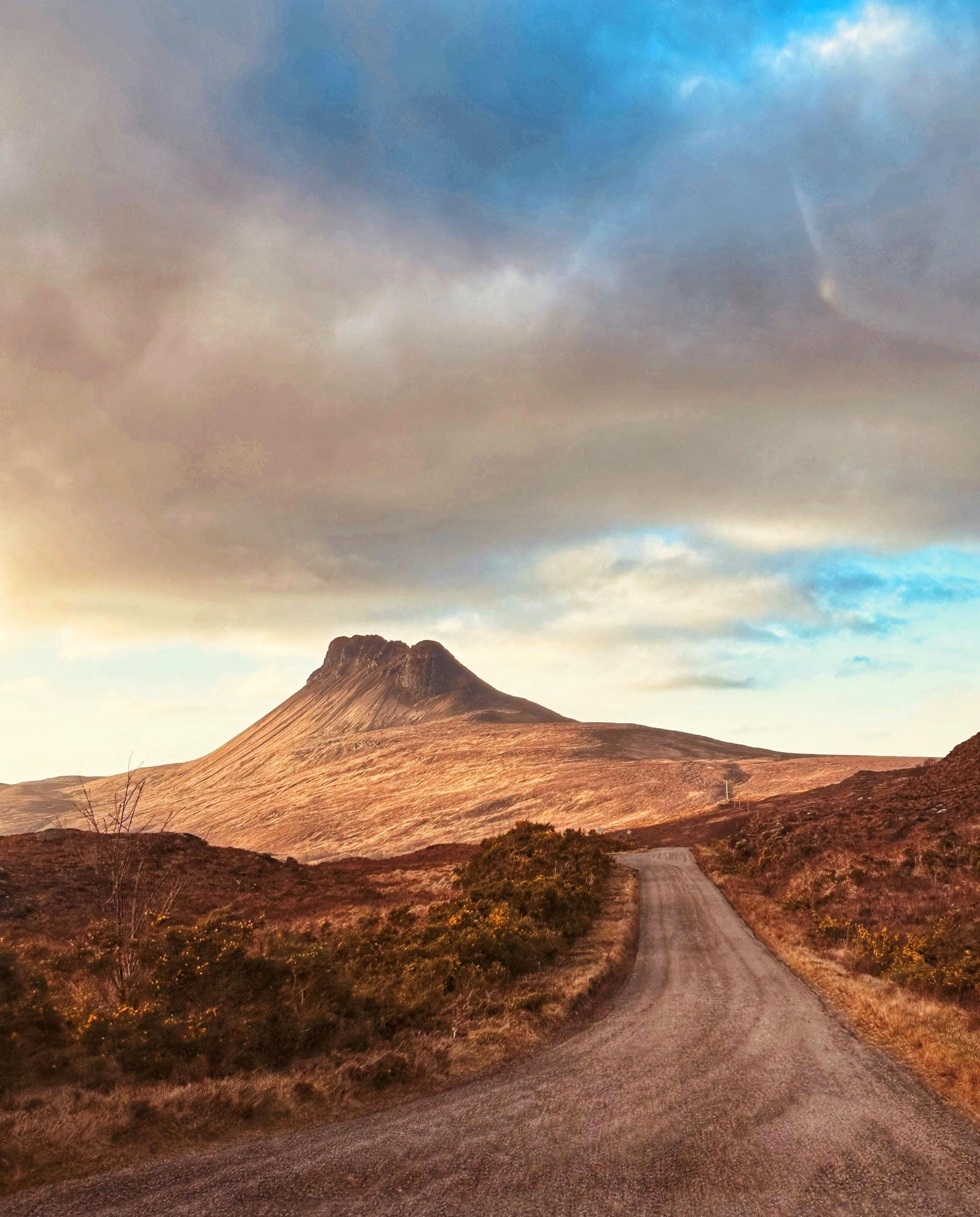 A mountain with a track in the foreground.