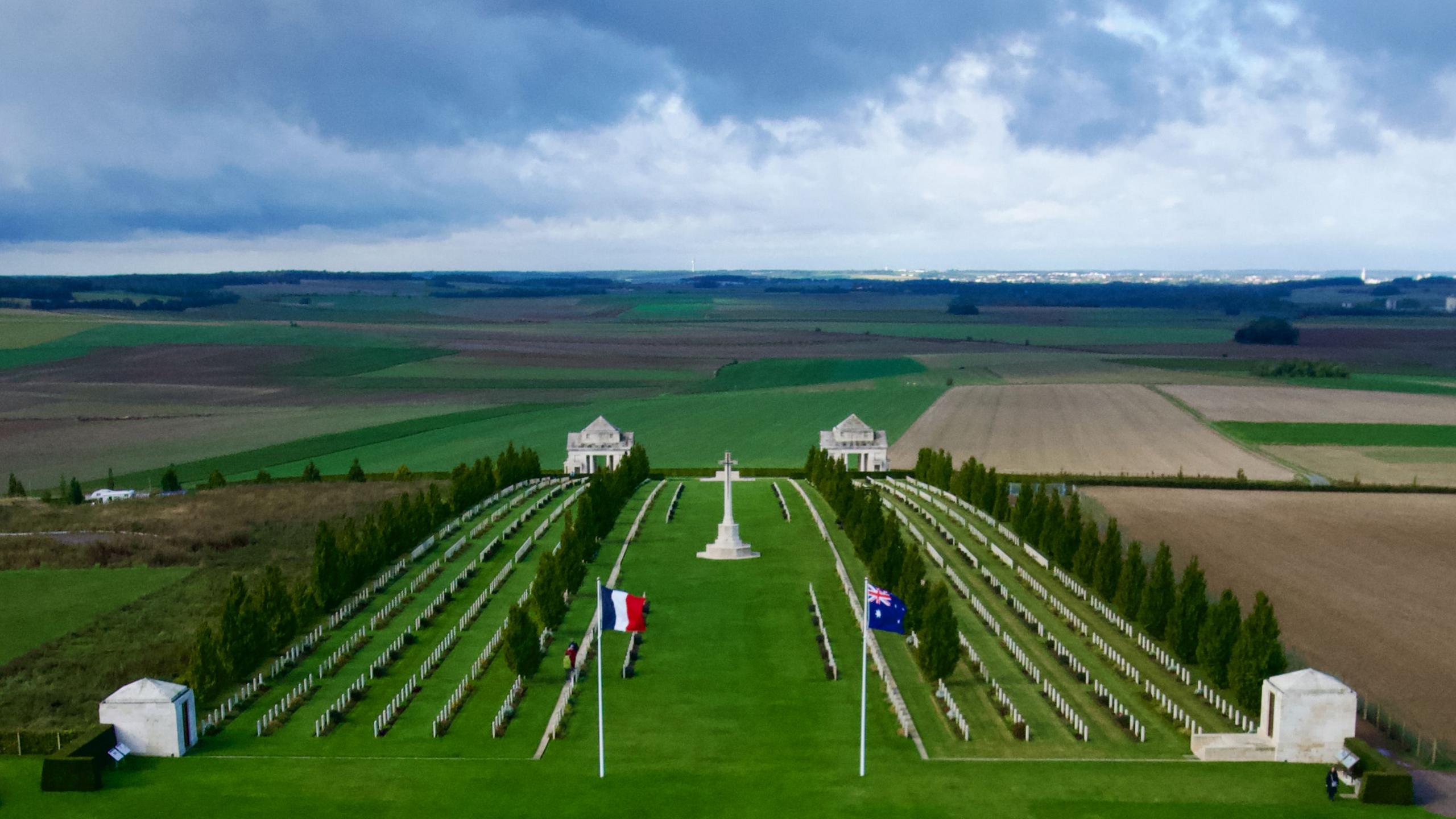 Rows of gravestones in a cemetery with French and Australian flags