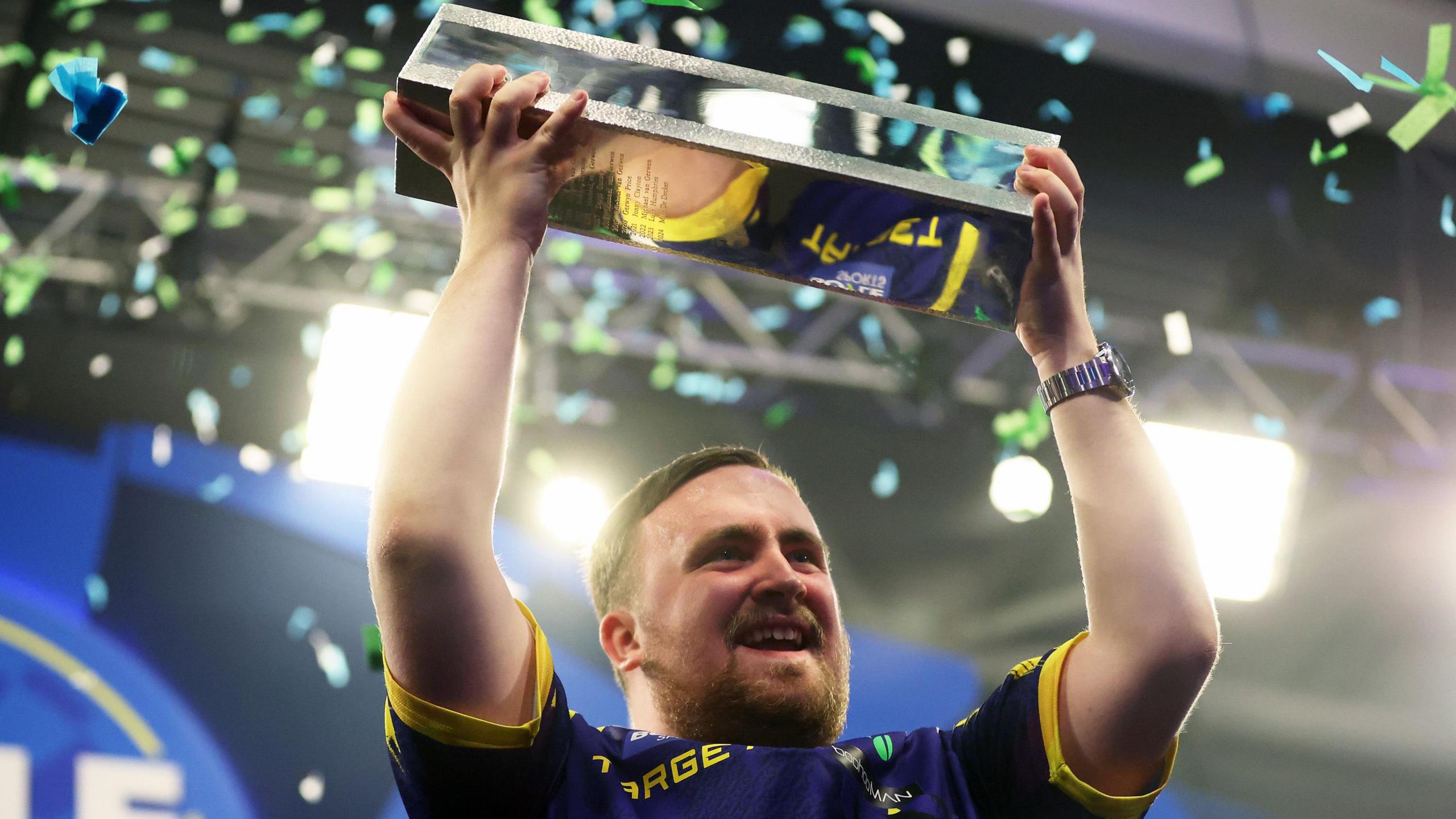 Luke Littler lifts the Grand Prix trophy aloft after winning the 2025 tournament