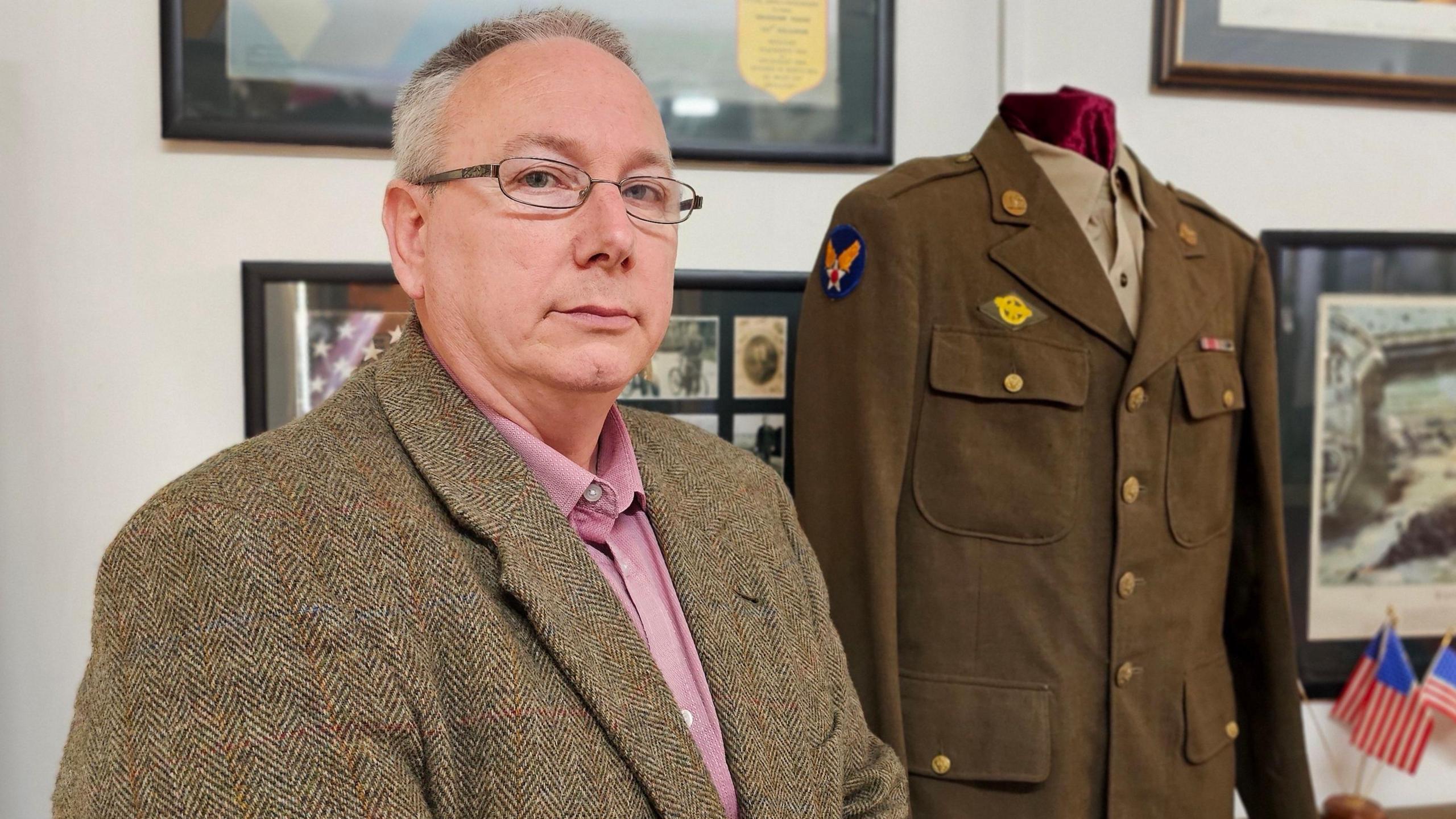 James Clarey standing in front of a serviceman's uniform.