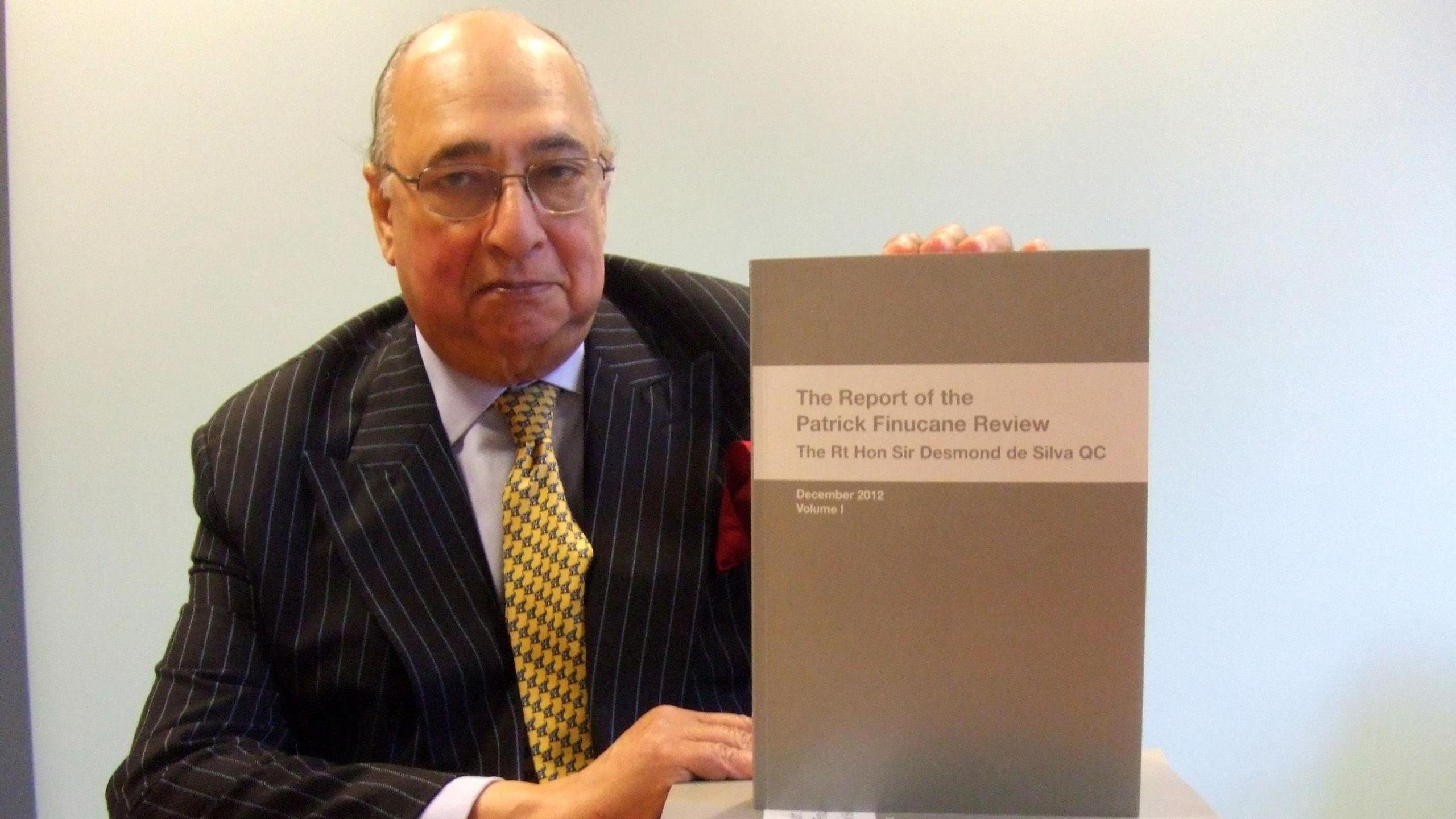 Sir Desmond de Silva holding up document entitled "The Report of the Patrick Finucane Review"