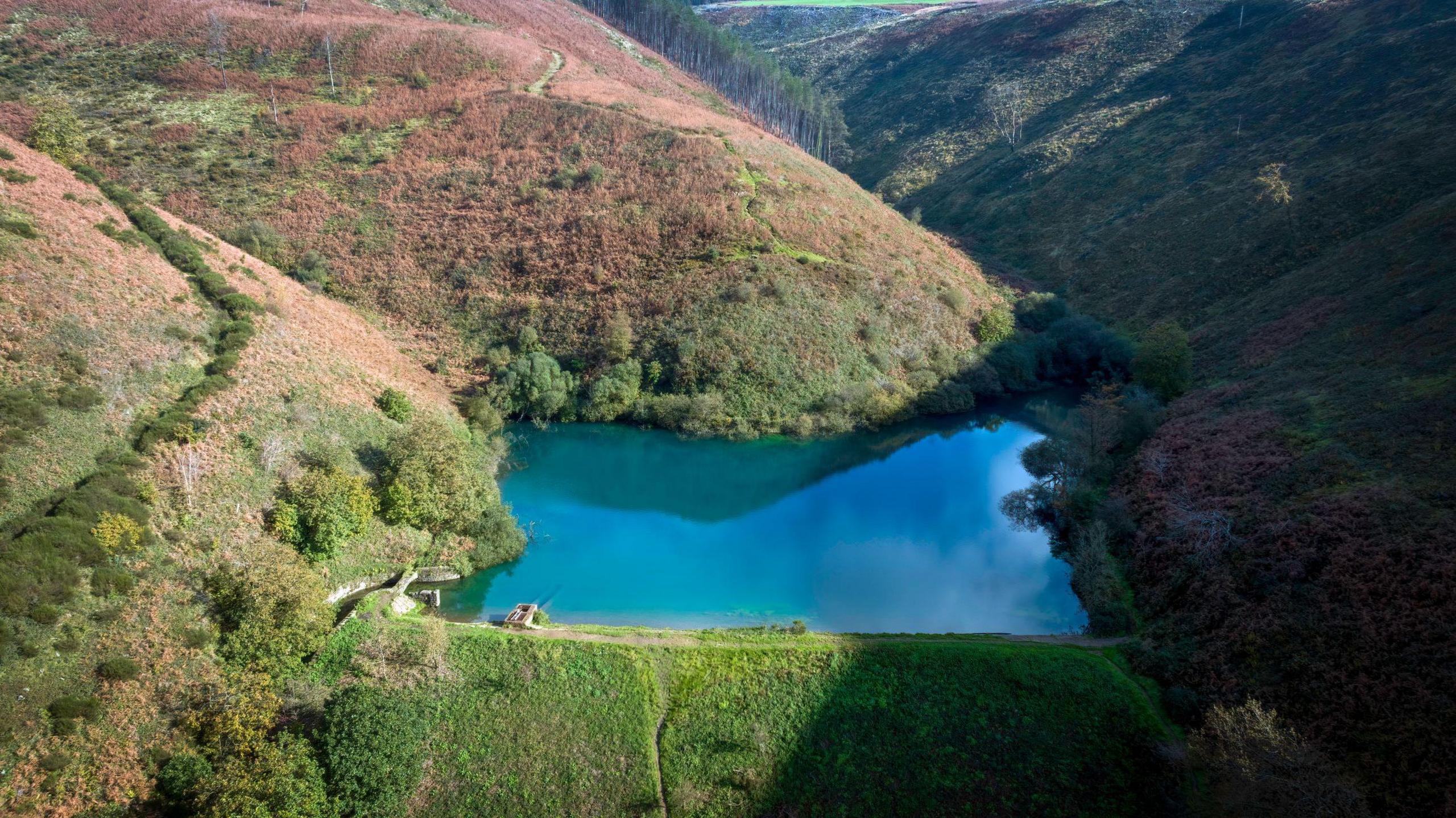 Brombil reservoir in the foothills of Margam  with blue waters surrounded by green forest and steep hills