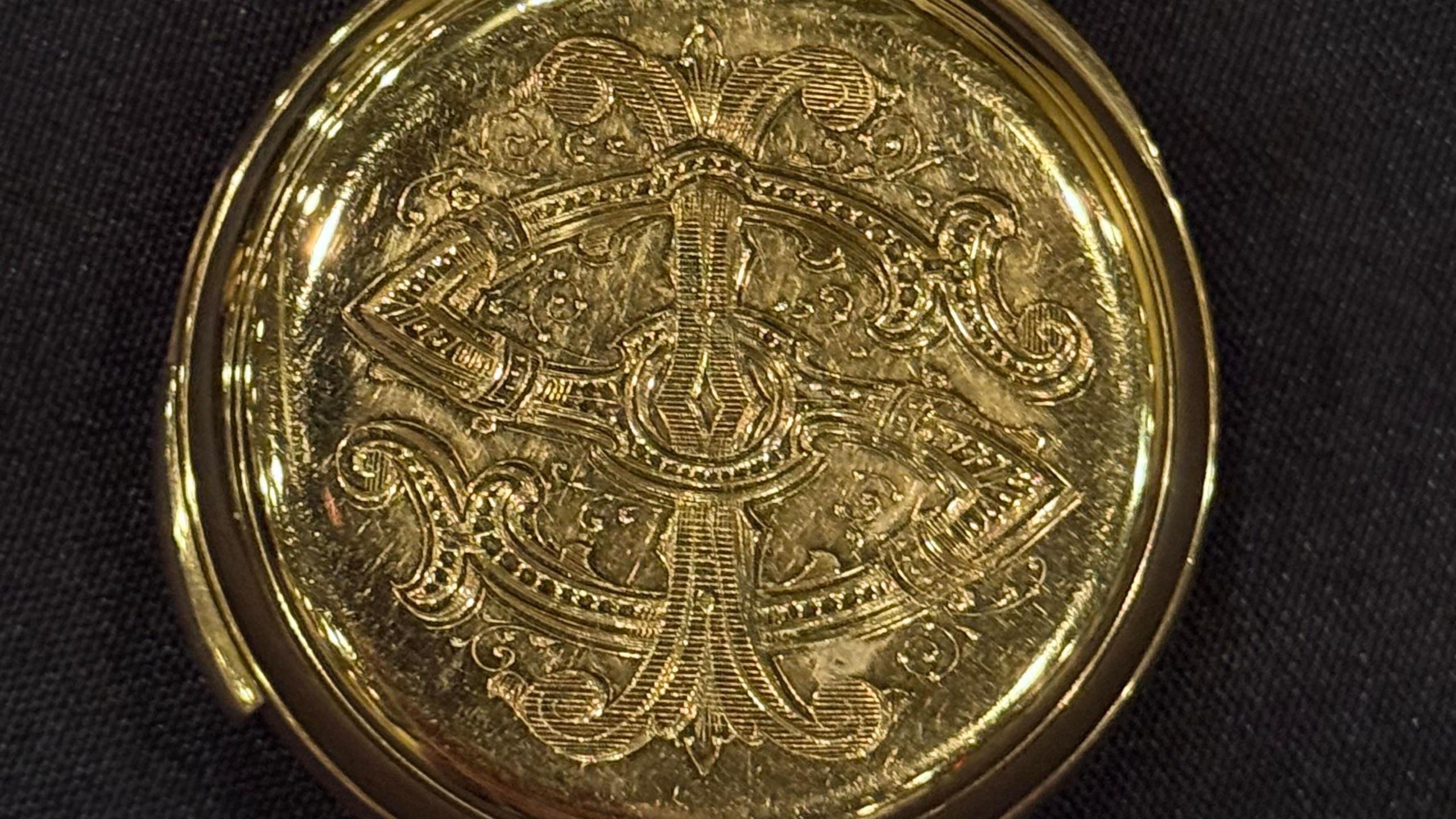 An artistic engraving on the outer casing of the golden watch.