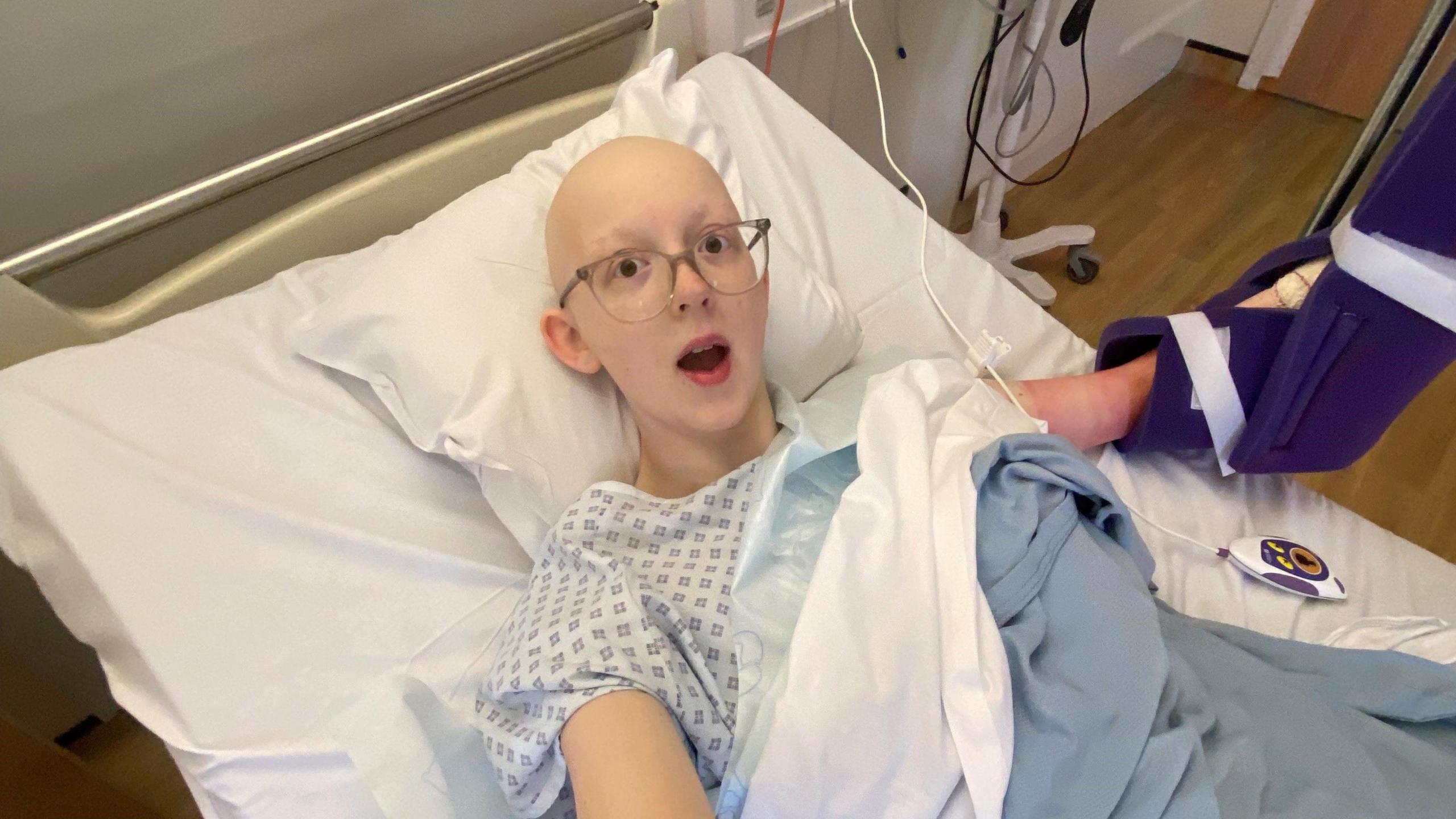 Ella Burns lies in a hospital bed. She has lost her hair.