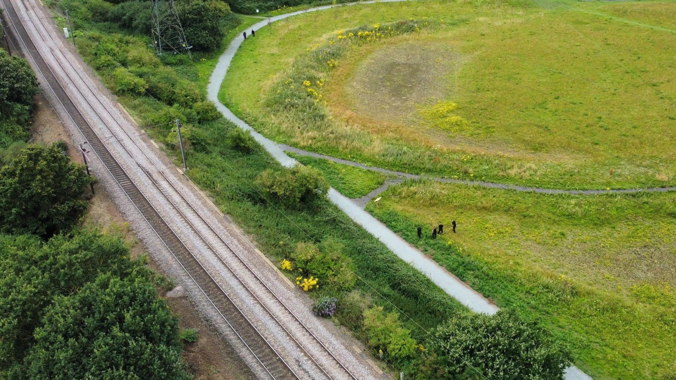 An aerial view of police in a field near the railway track where the incident happened